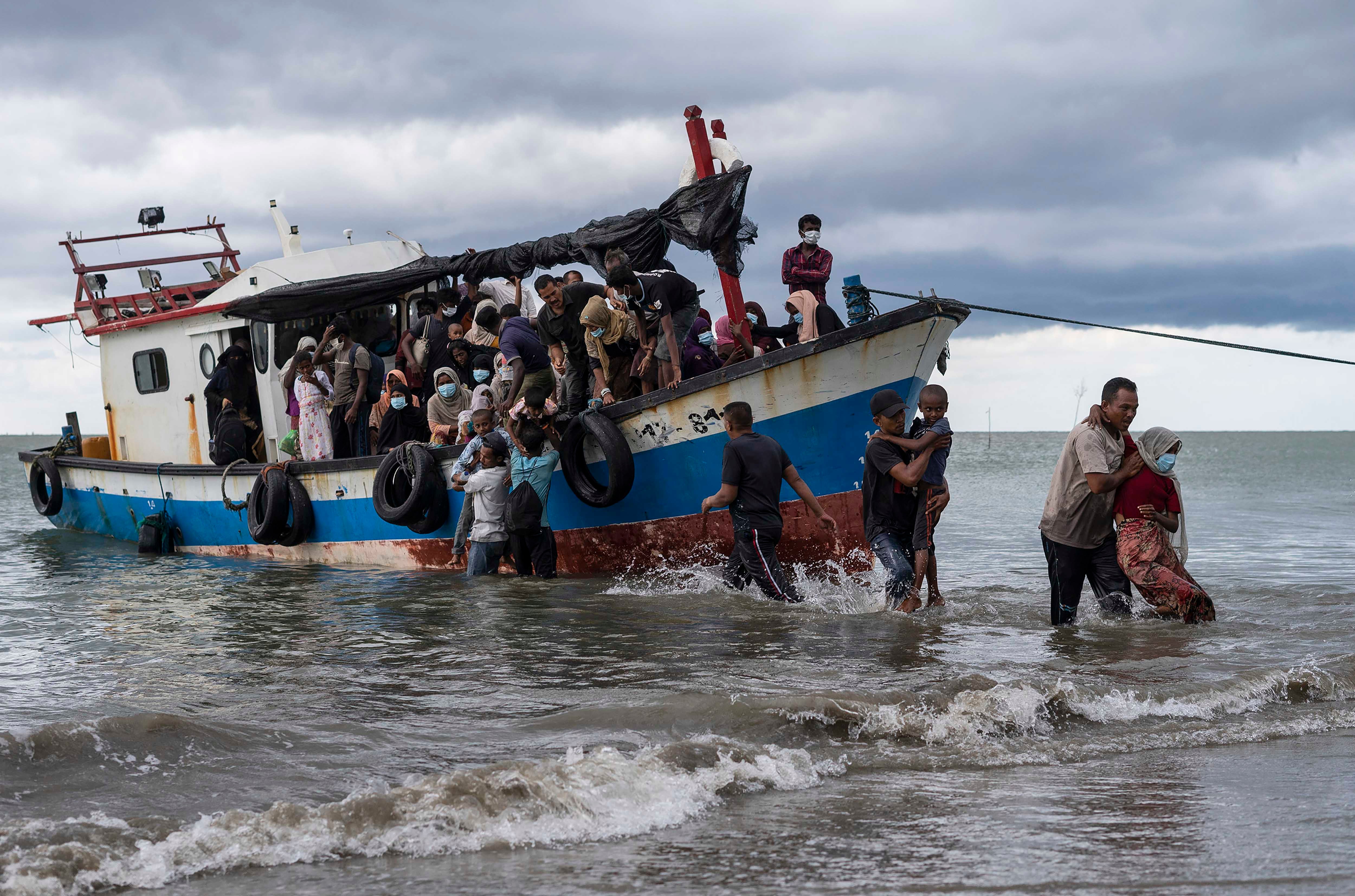 Local fishermen help Rohingya asylum seekers as they arrive in North Aceh, Indonesia, June 25, 2020.