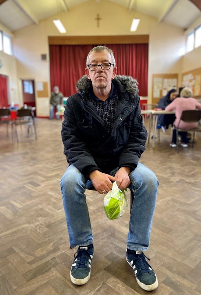 A man in a jacket and glasses sits while posing for the camera