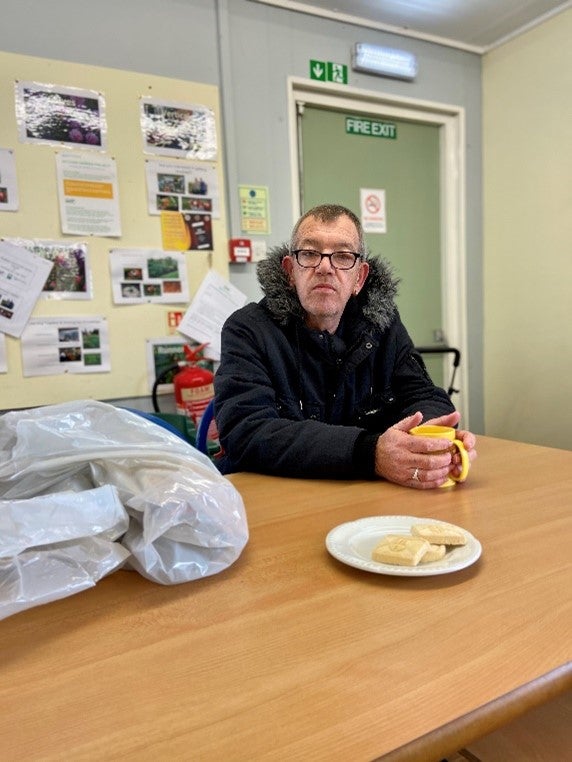 A man in glasses and a coat sits in front of a table
