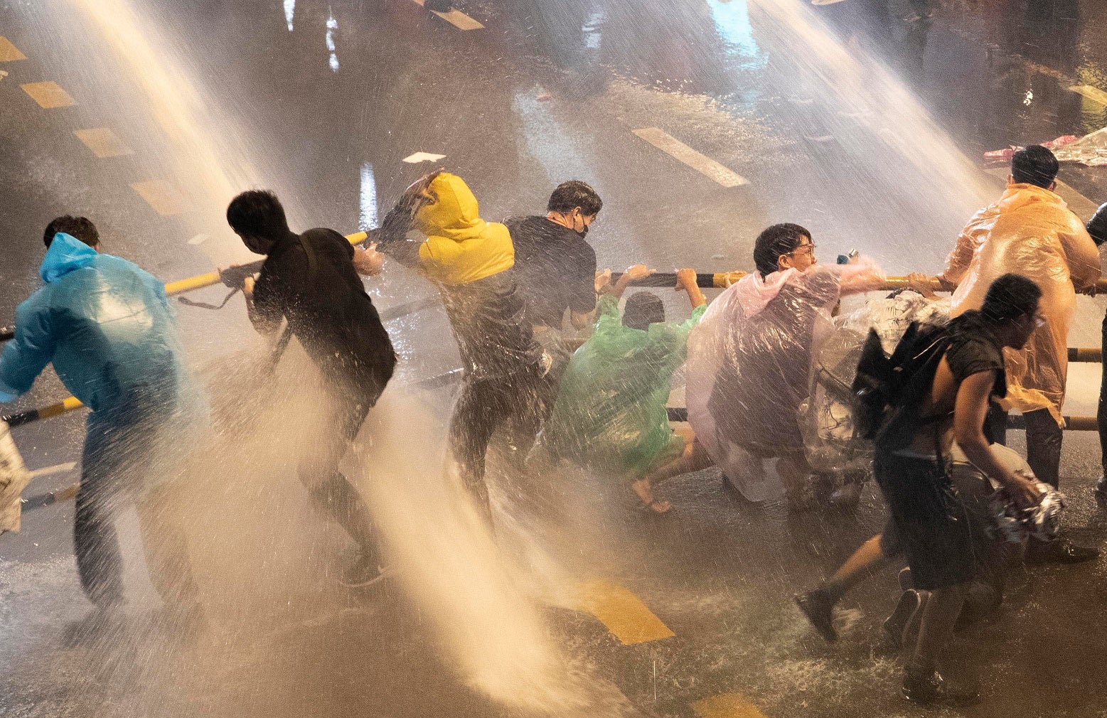 Pro democracy demonstrators face water canons as police try to clear the protest venue in Bangkok, Thailand, Friday, Oct. 16, 2020. 