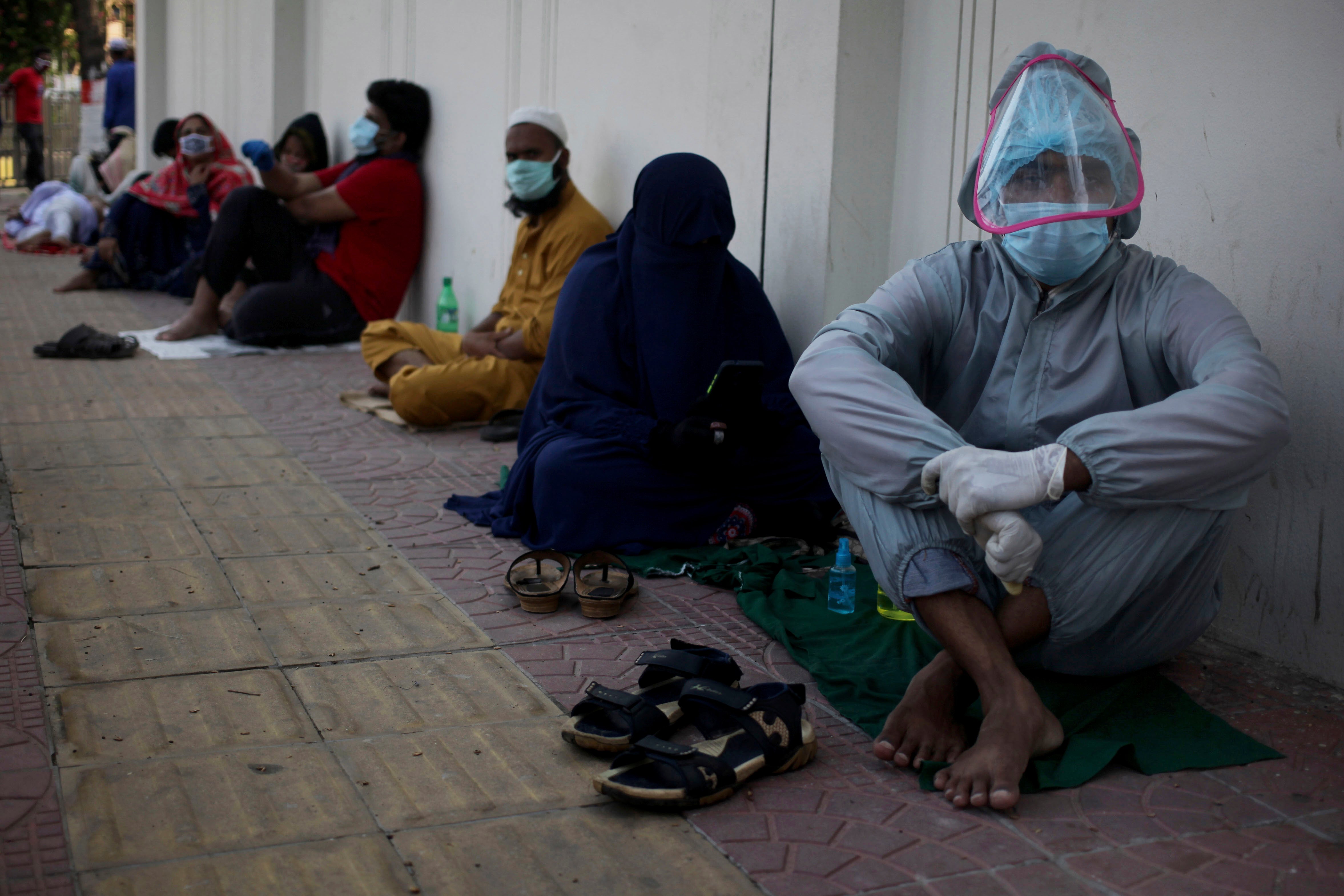 People in face masks seated on the floor in a line 
