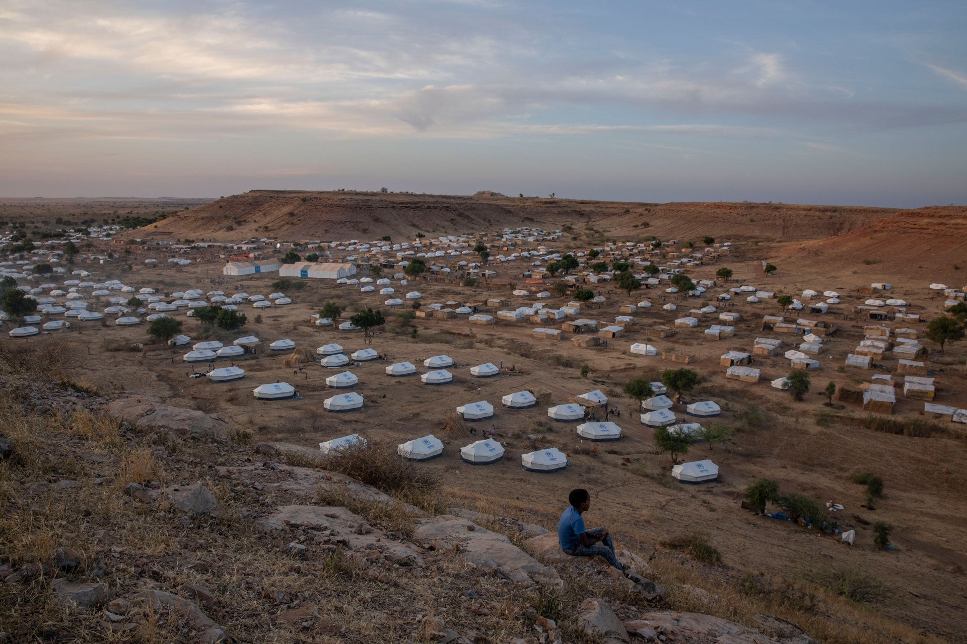 A boy sits atop a hill overlooking part of Um Raquba refugee camp, hosting people who fled the conflict in the Tigray region of Ethiopia, in al-Gadaref state, eastern Sudan, December 14, 2020. 