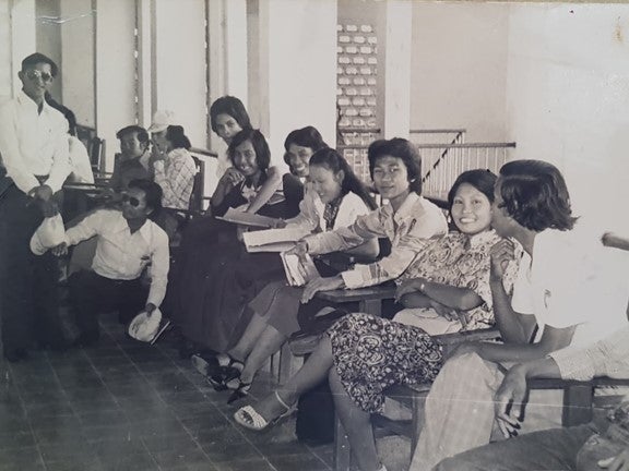 College students at desks smile for a photo