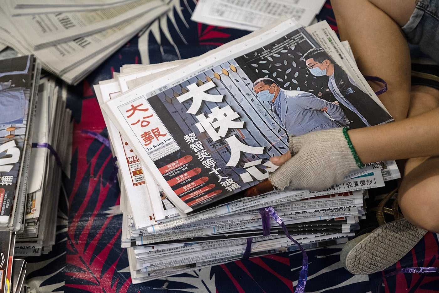 A vendor handles a copy of the Ta Kung Pao newspaper on August. 11, 2020. The day before, Hong Kong police arrested Next Digital Ltd. Chairman Jimmy Lai and several of his top executives for allegedly violating the National Security Law, and sent hundreds of officers to search the Apple Daily newspaper's offices. The Ta Kung Pao front headline reads, "Very Happy!" 