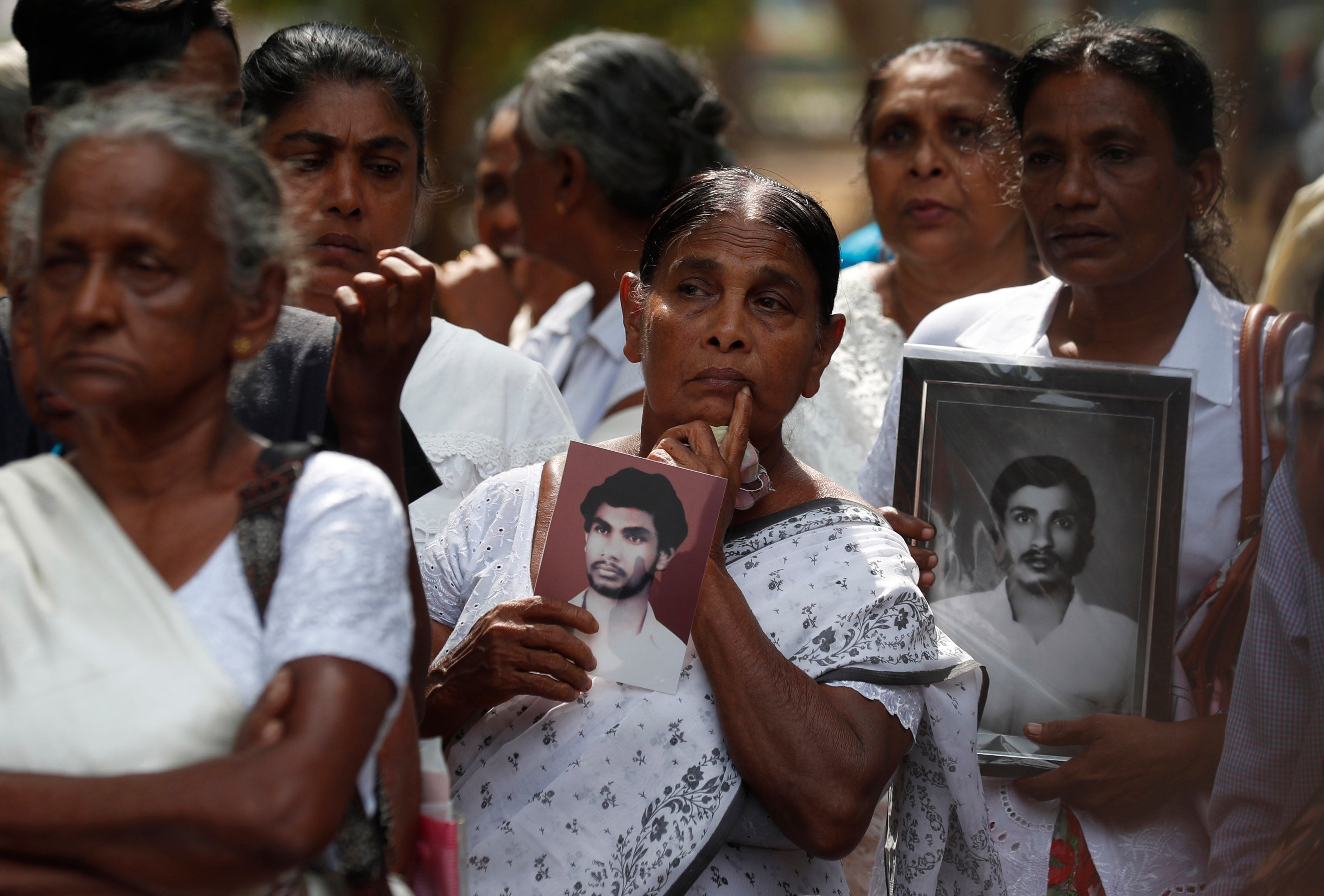 A group of women holding black-and-white photos of men