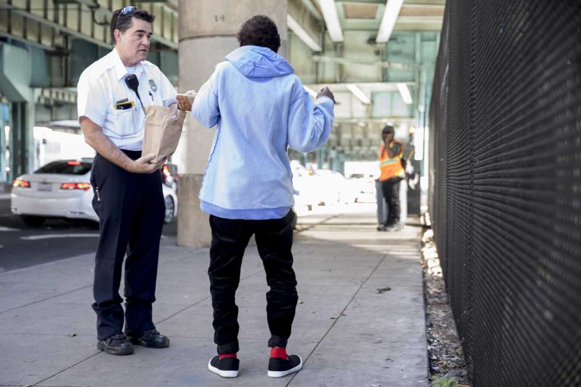 A worker offers food to a homeless woman while escorting her into S.F.’s Division Navigation Center in January 2020.