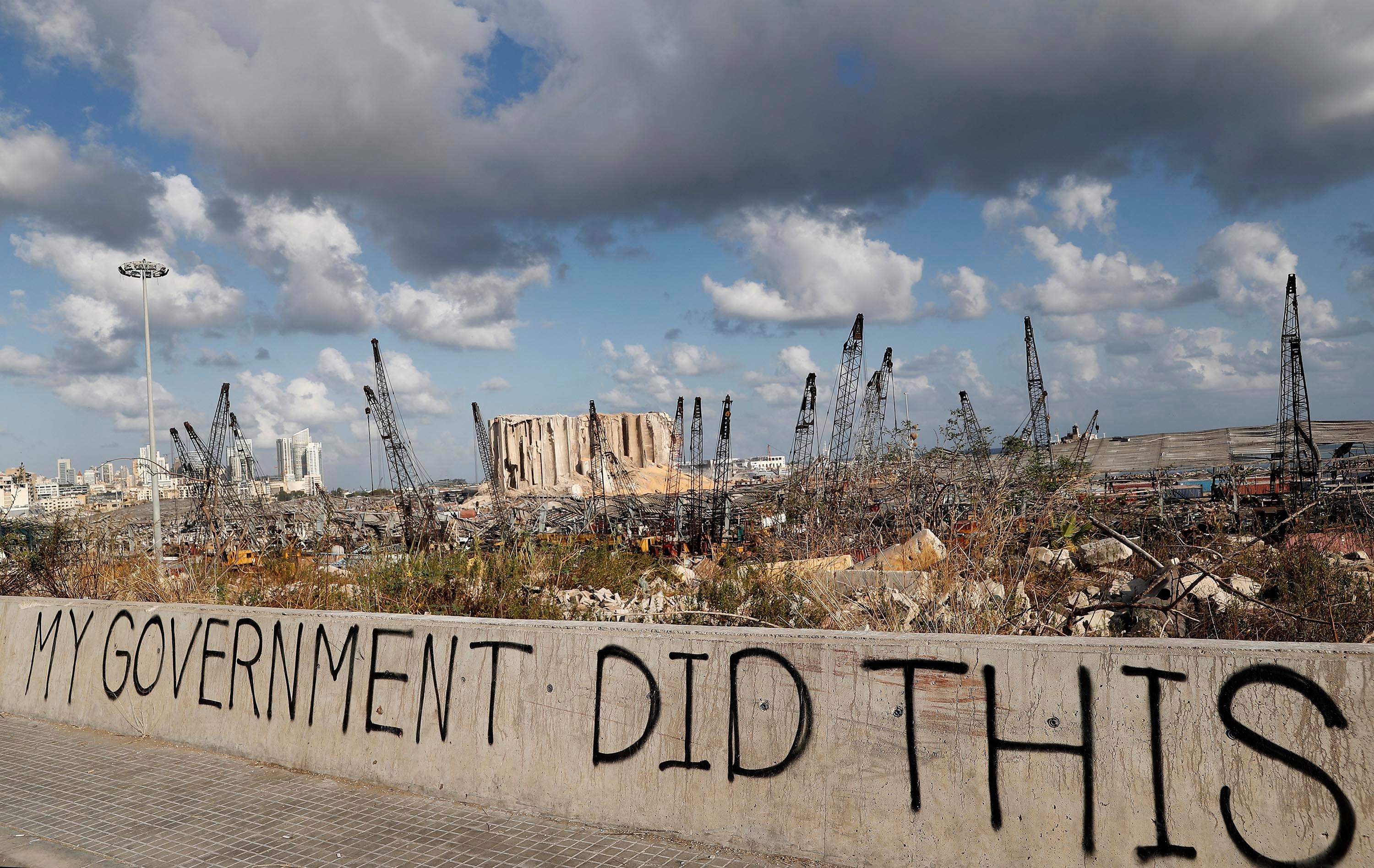 In this Aug. 9, 2020 file photo, political graffiti is visible in front of the scene of the August 4 explosion that hit the seaport of Beirut, Lebanon