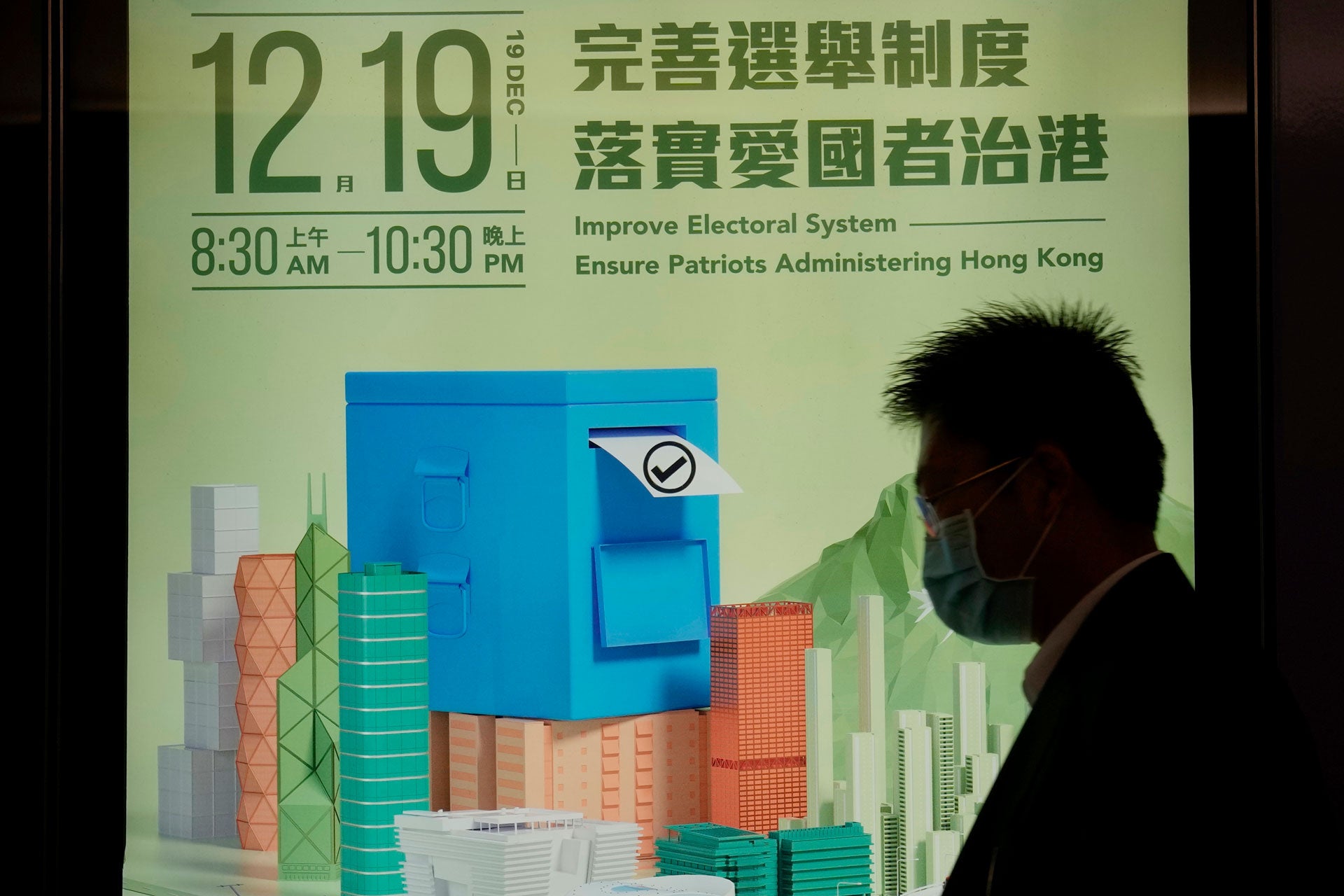A man walks past a poster promoting the upcoming legislative elections in Hong Kong