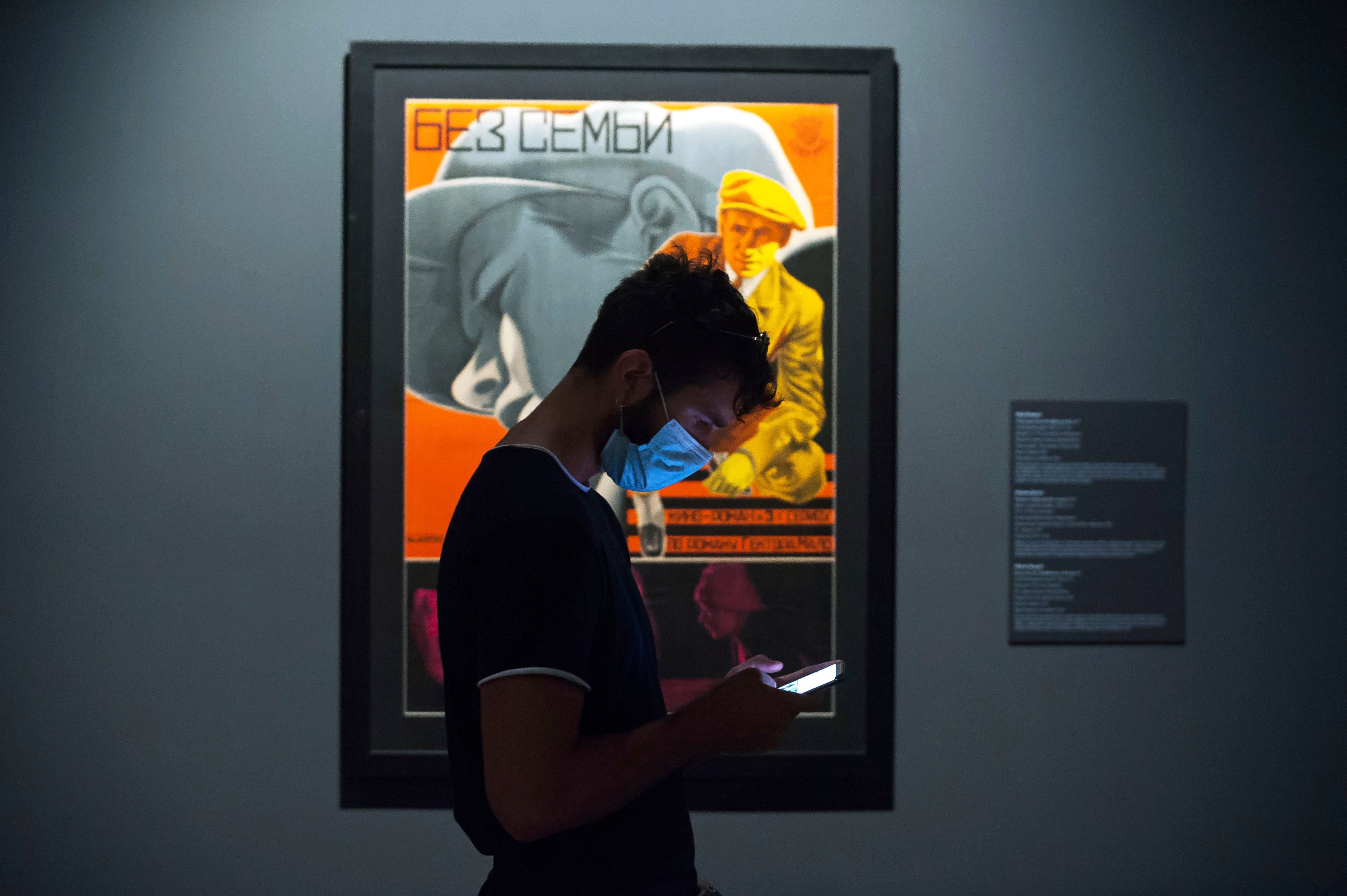 Молодой человек в маске проверяет свой мобильный телефон в Государственном Русском музее, Санкт-Петербург, 26 мая 2020 года.