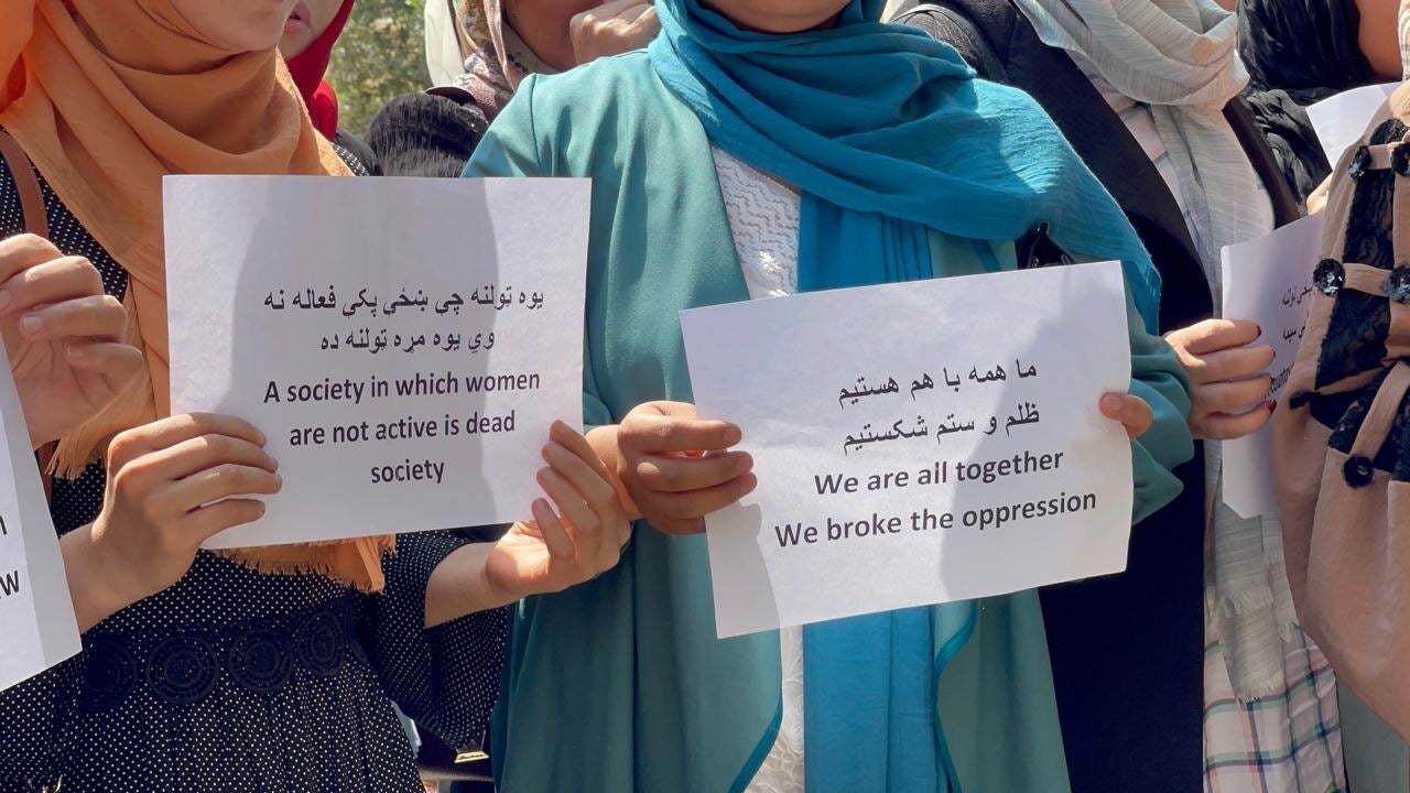 Two women hold protest signs 