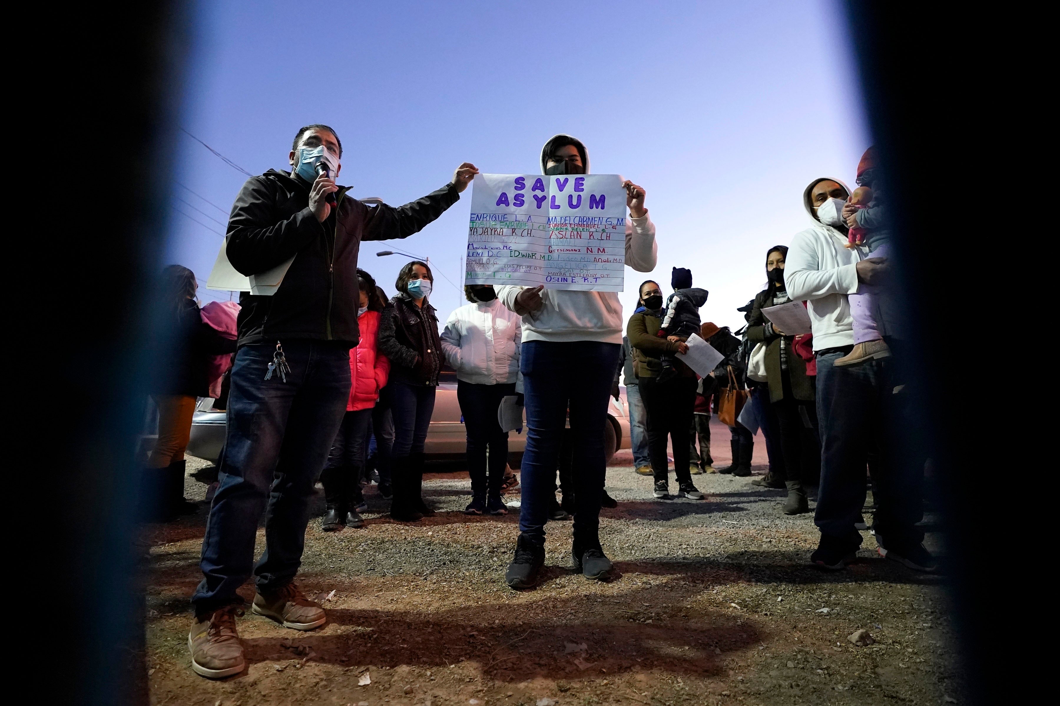 People hold a protest sign that reads "Save asylum" 