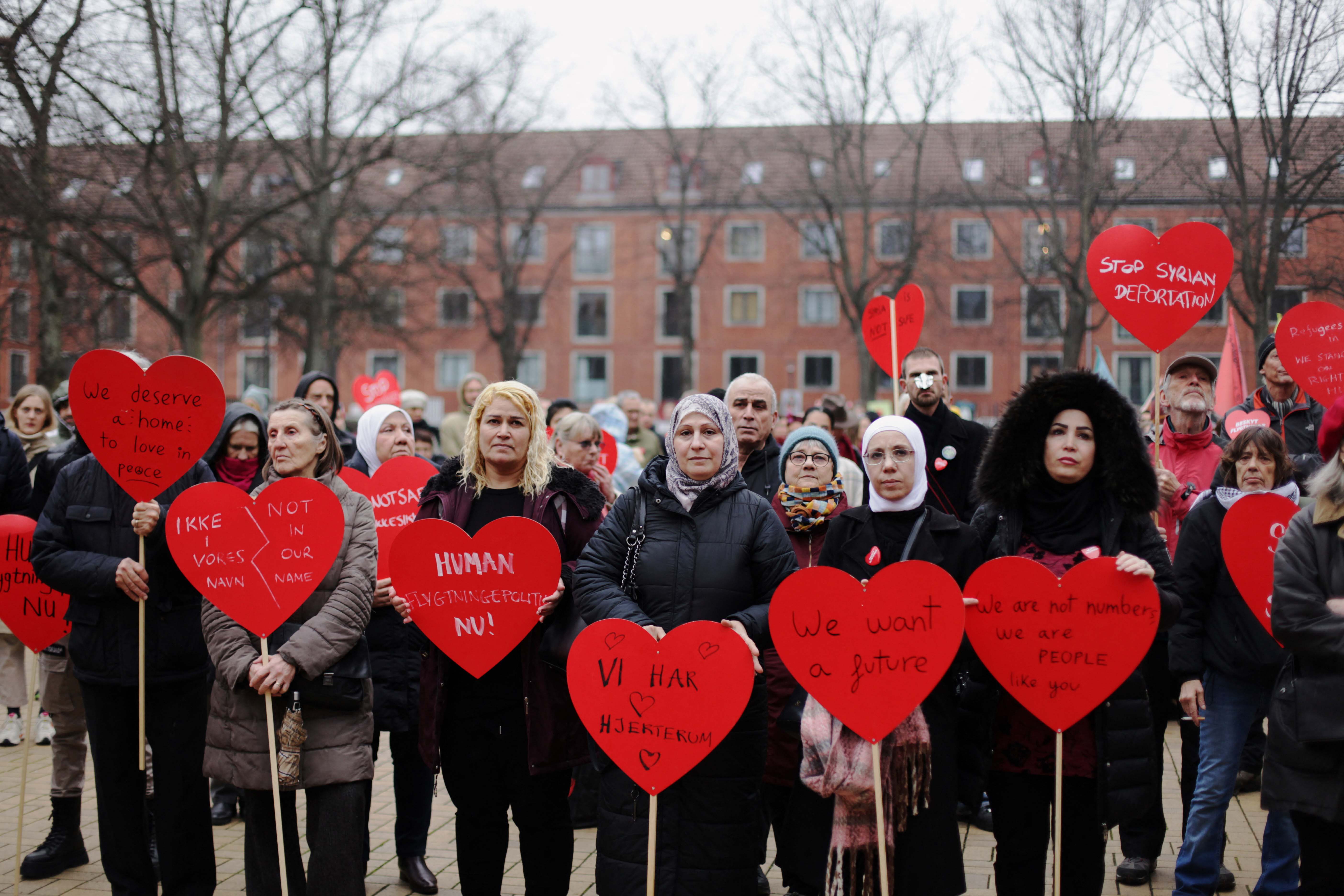 Protesters hold red heart-shaped signs