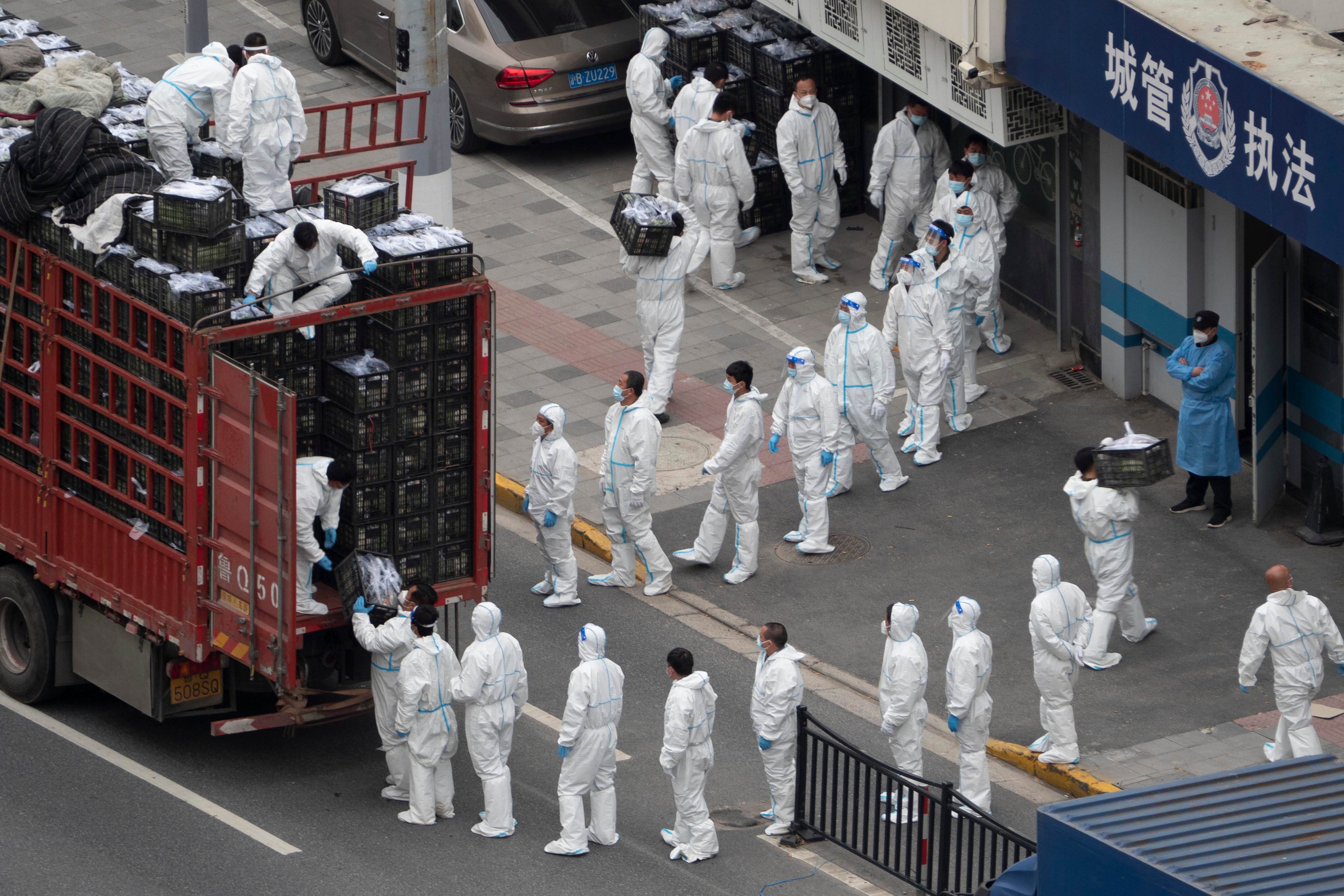 People in PPE load groceries off a truck before distributing them to locals under the Covid-19 lockdown in Shanghai, China, April 5, 2022.