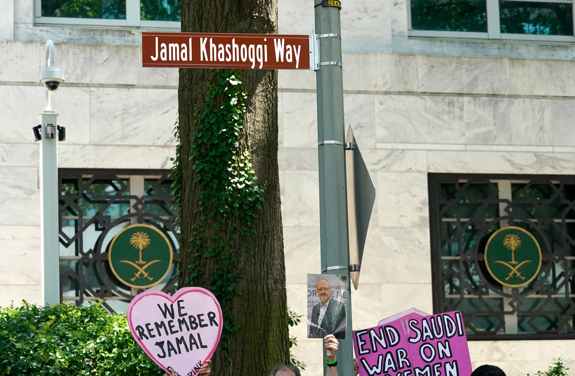 People hold placards in front of a new street sign reading Jamal Khashoggi Way
