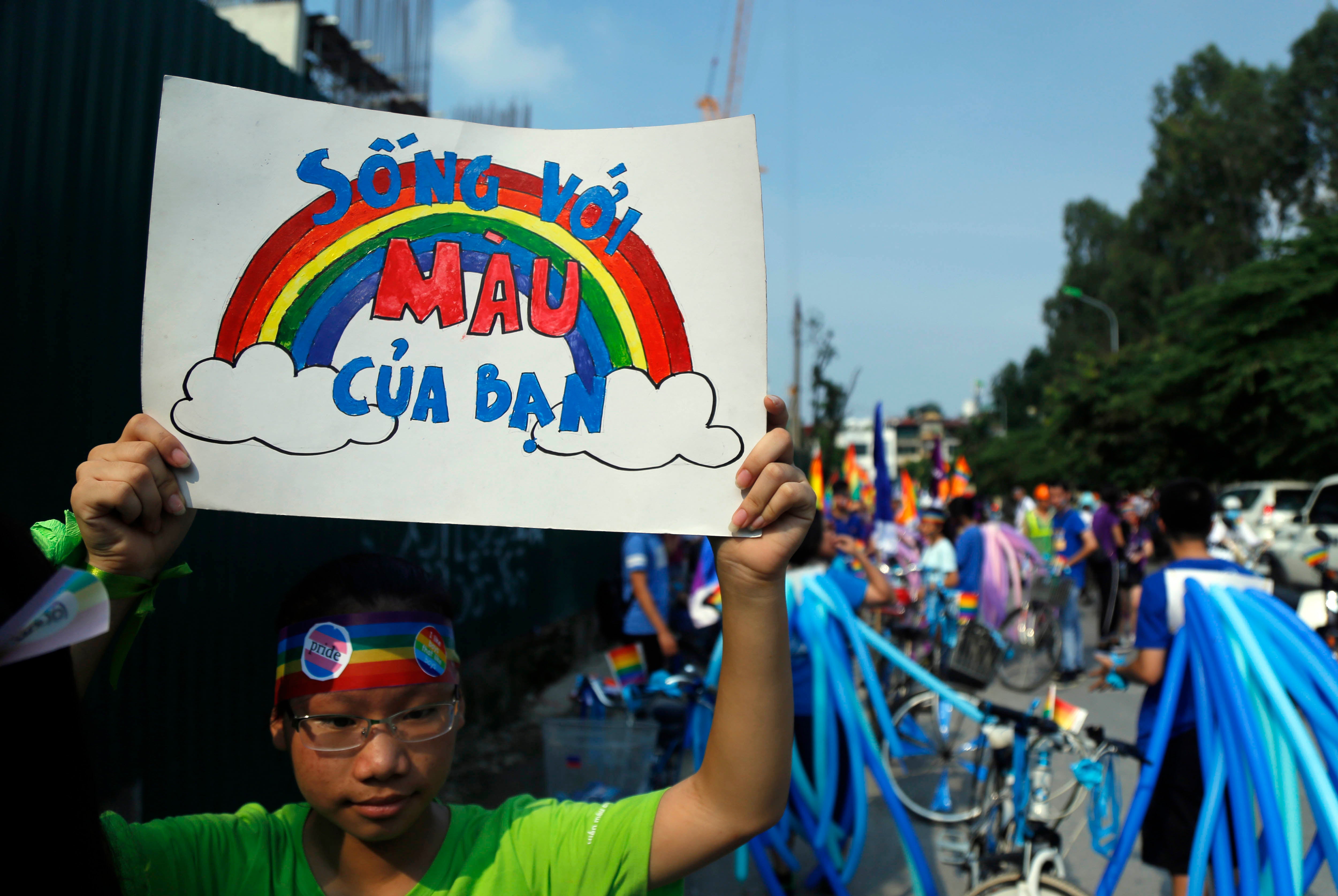 A cyclist holds up a poster reading in Vietnamese, "Shine your true colors," ahead of a bike rally in Hanoi, Vietnam, September 24, 2017. 