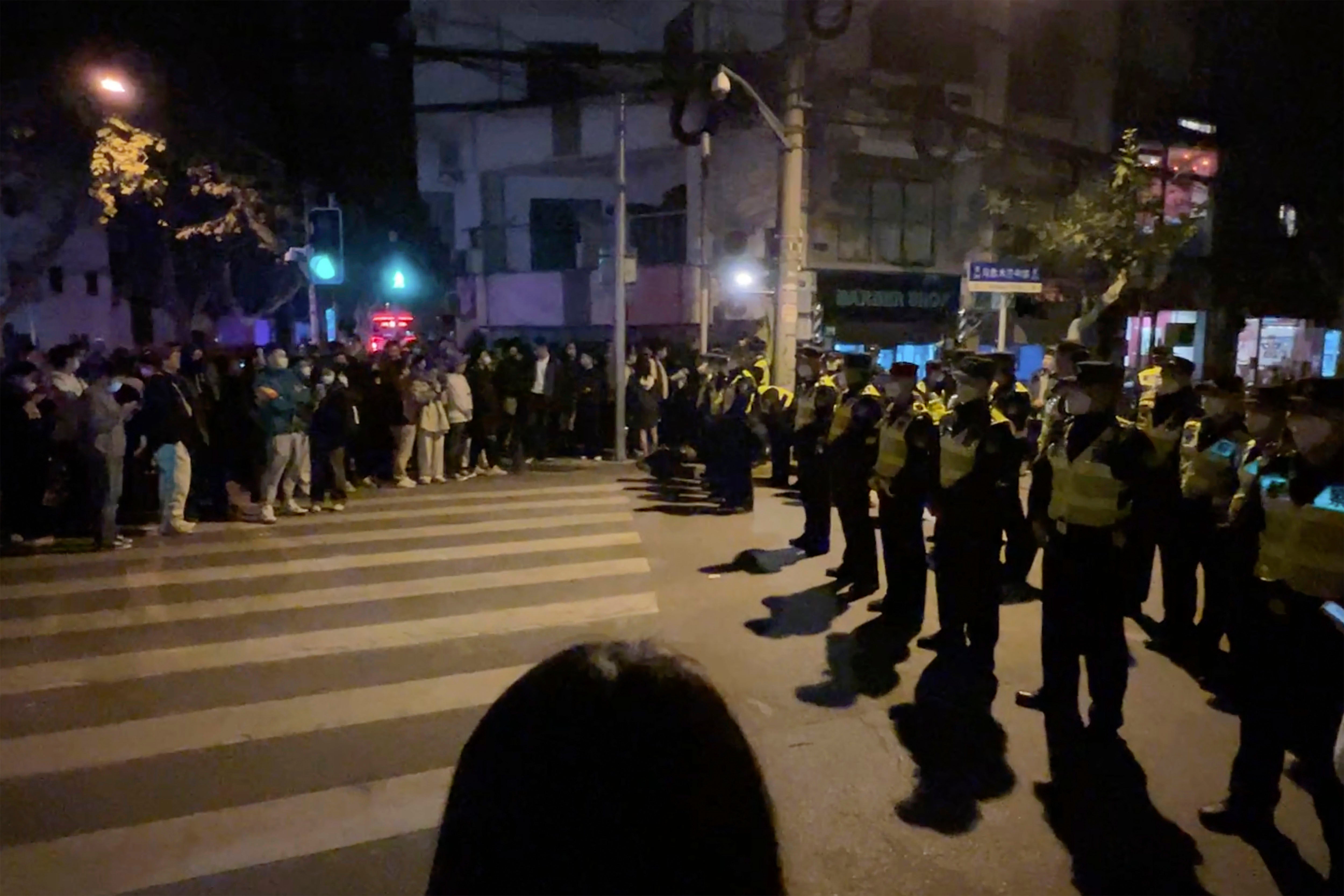 Chinese police officers block off access to a site where protesters had gathered in Shanghai on November 27, 2022.