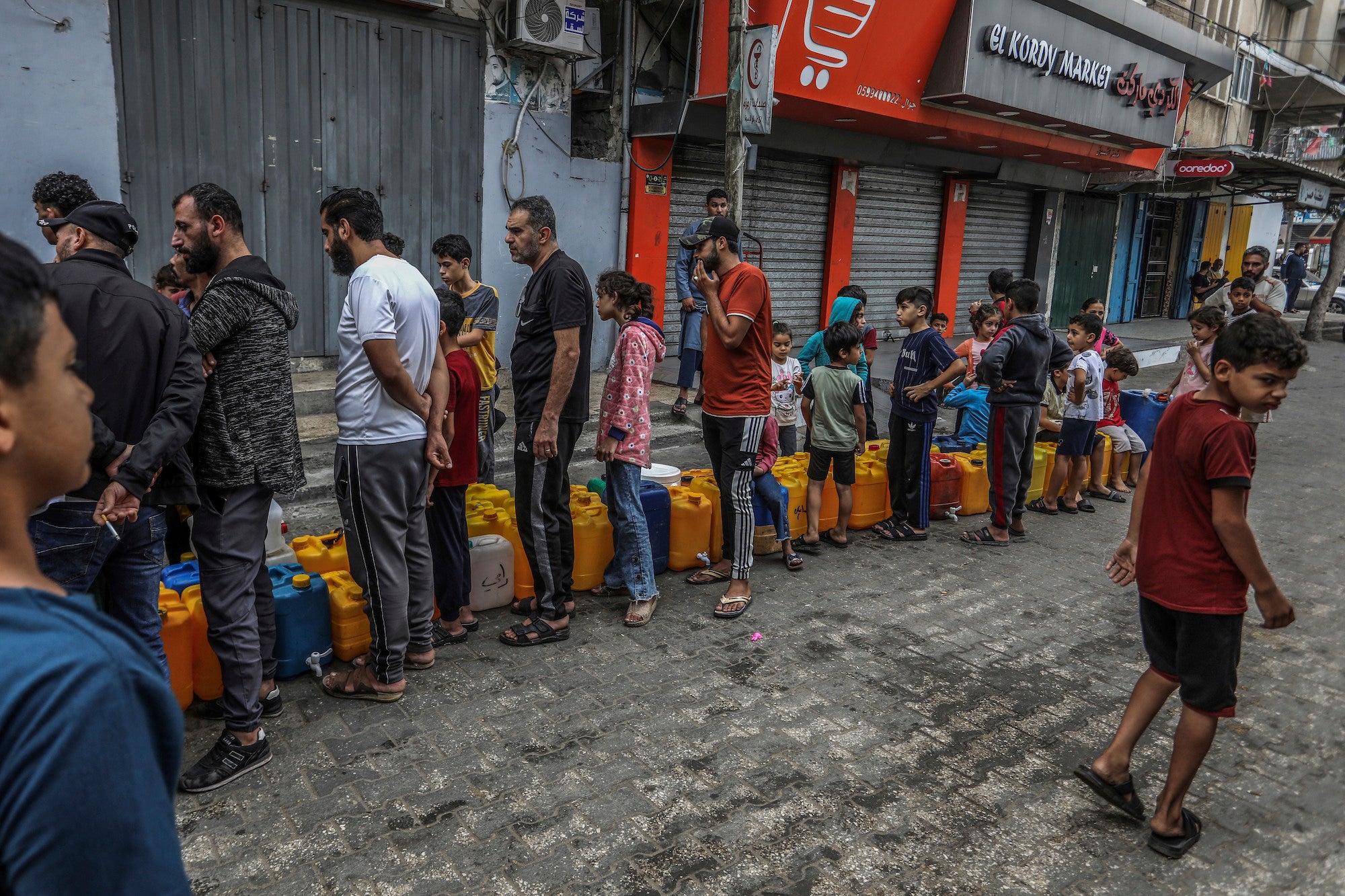 Palestinians stand in line to get water in the city of Rafah in the southern Gaza Strip amid ongoing hostilities between Israeli forces and Palestinian armed groups, November 13, 2023. 