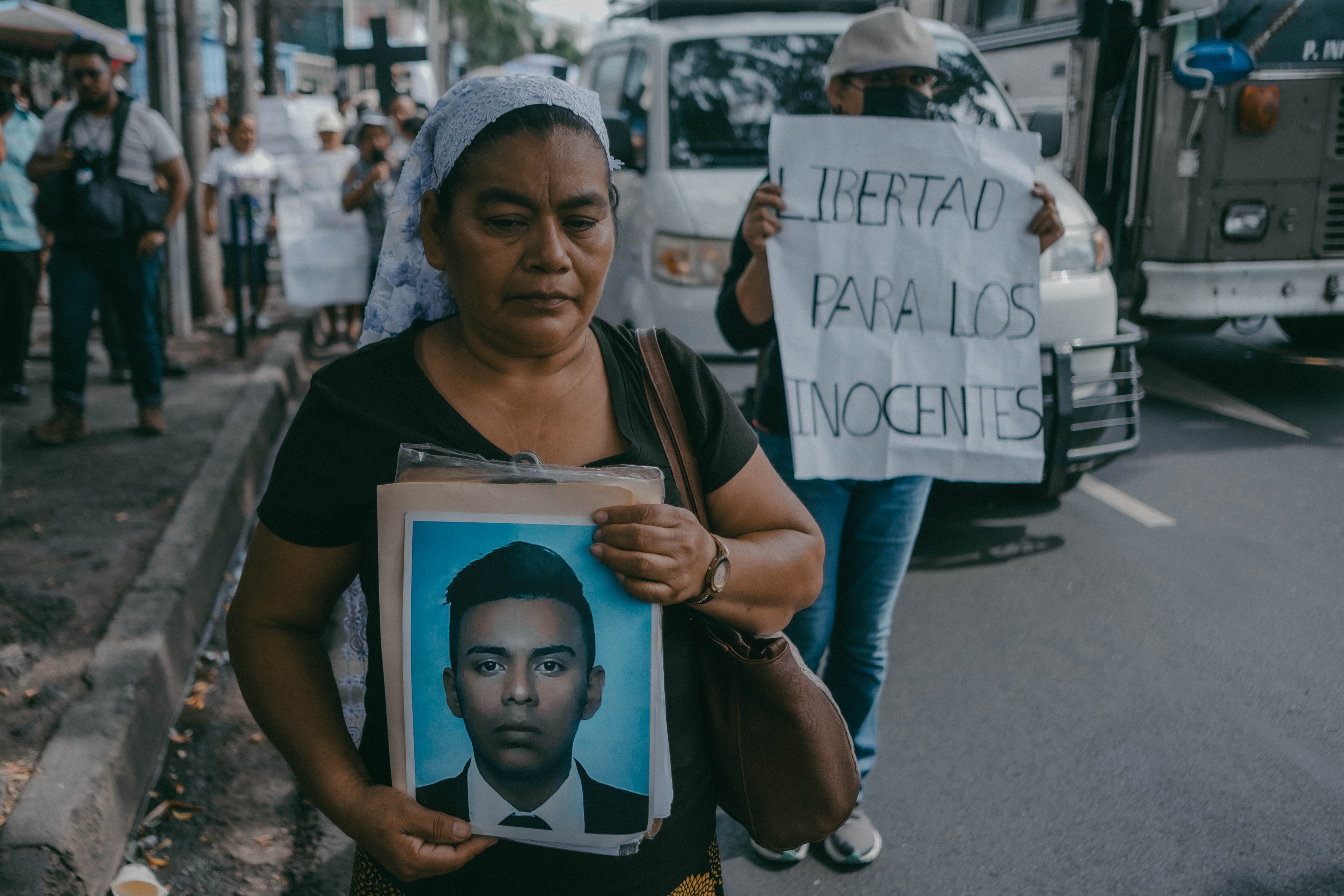 A woman holds a photo of her son at a protest