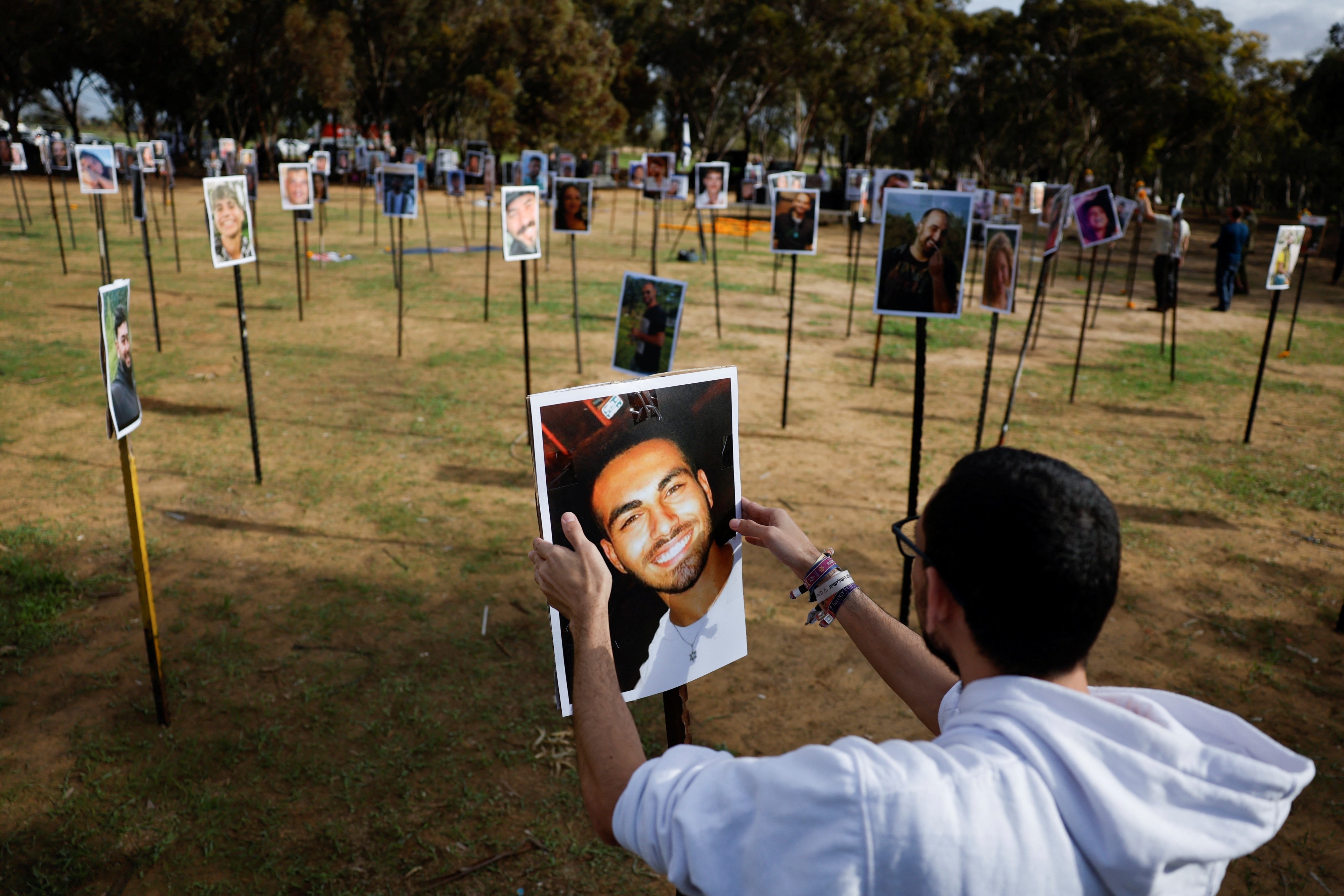 A man installs a portrait at a memorial in a field