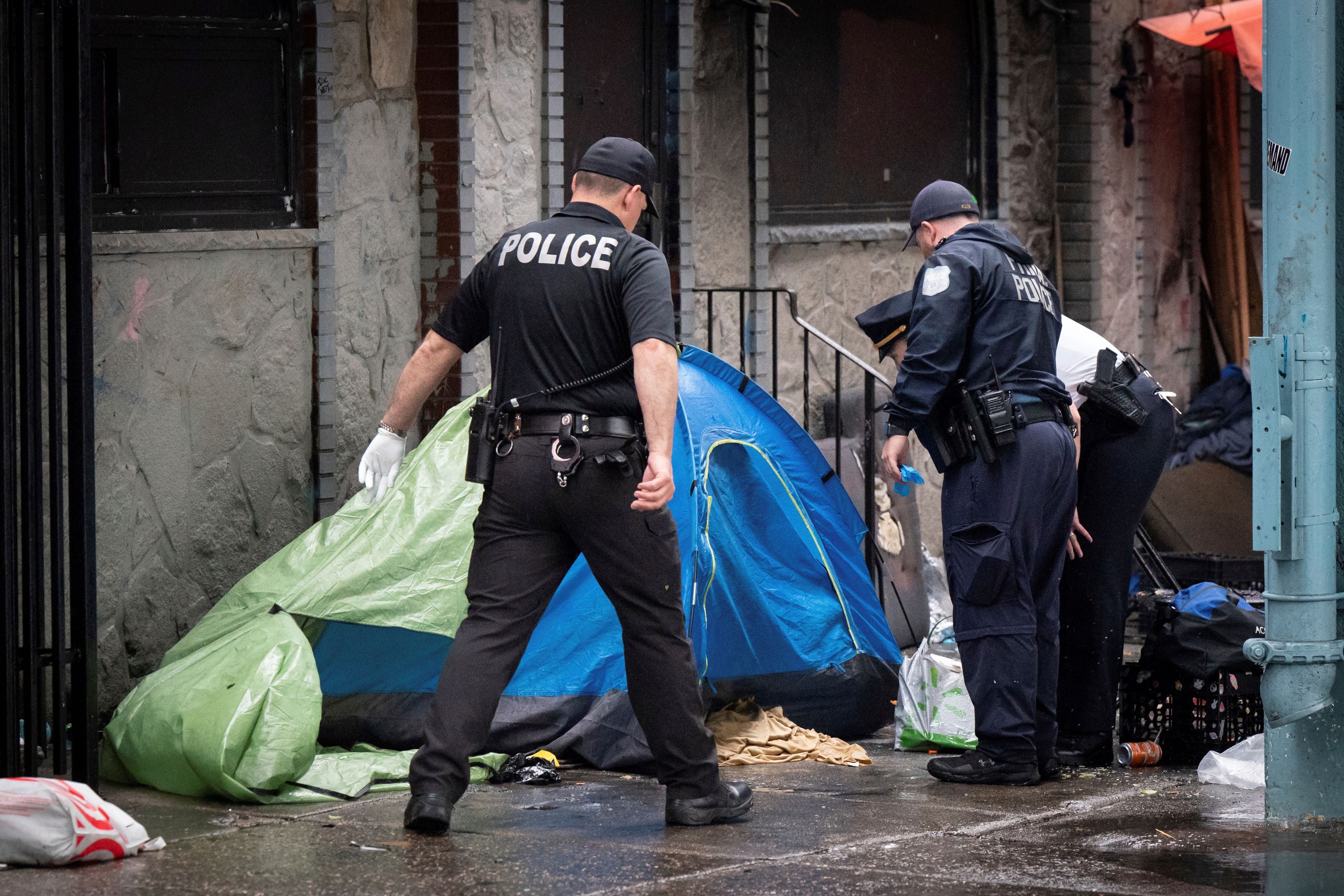 Police look into a tent at an encampment for unhoused people