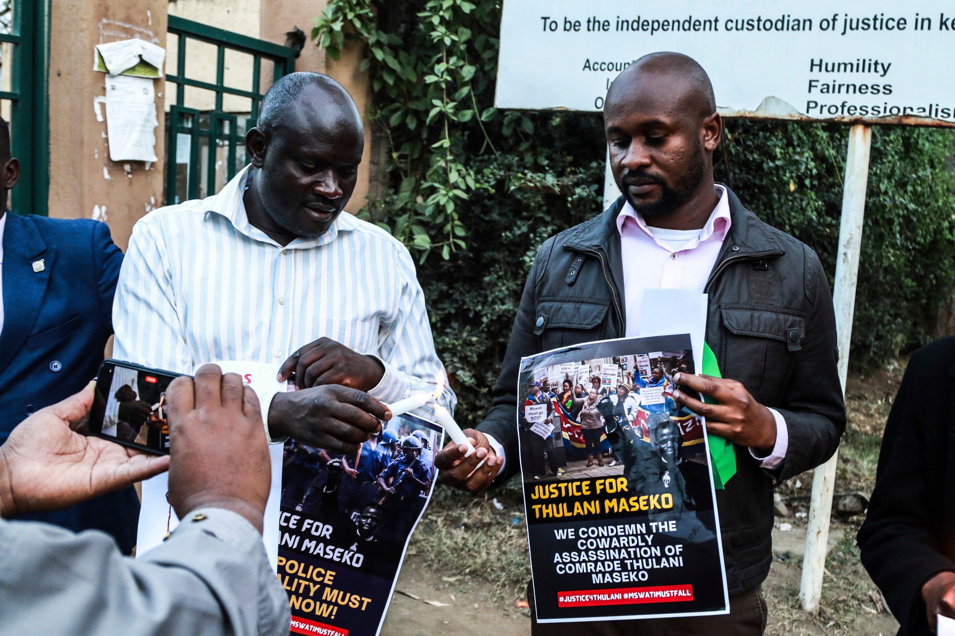 Activists light candles while holding posters at a tribute to the assassinated human rights lawyer Thulani Maseko, Eswatini, formerly Swaziland