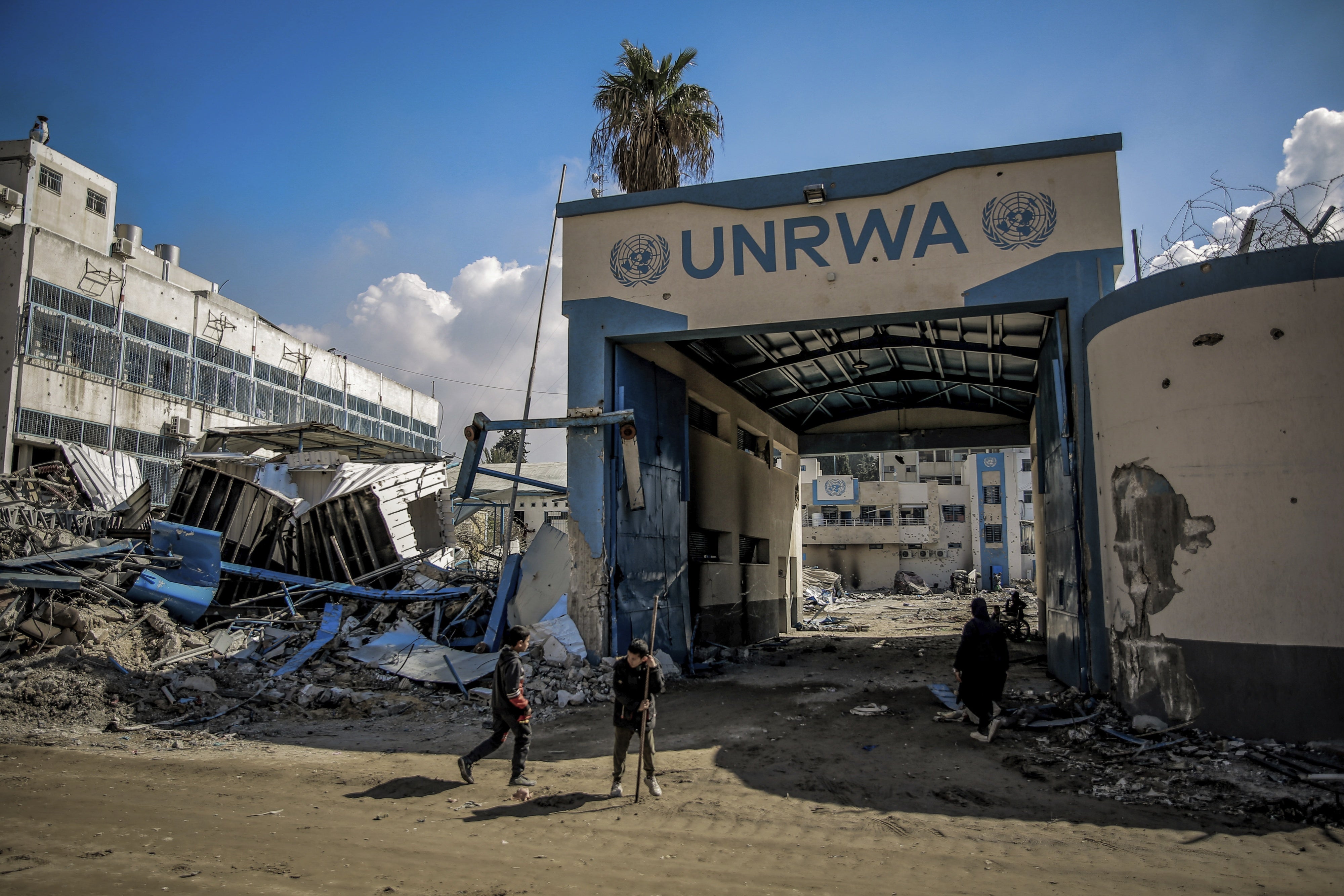 Des Palestiniens passaient devant les décombres d’un bâtiment de l'Office de secours et de travaux des Nations Unies pour les réfugiés de Palestine dans le Proche-Orient (UNRWA) dans la ville de Gaza, suite à une frappe israélienne, le 10 février 2024.