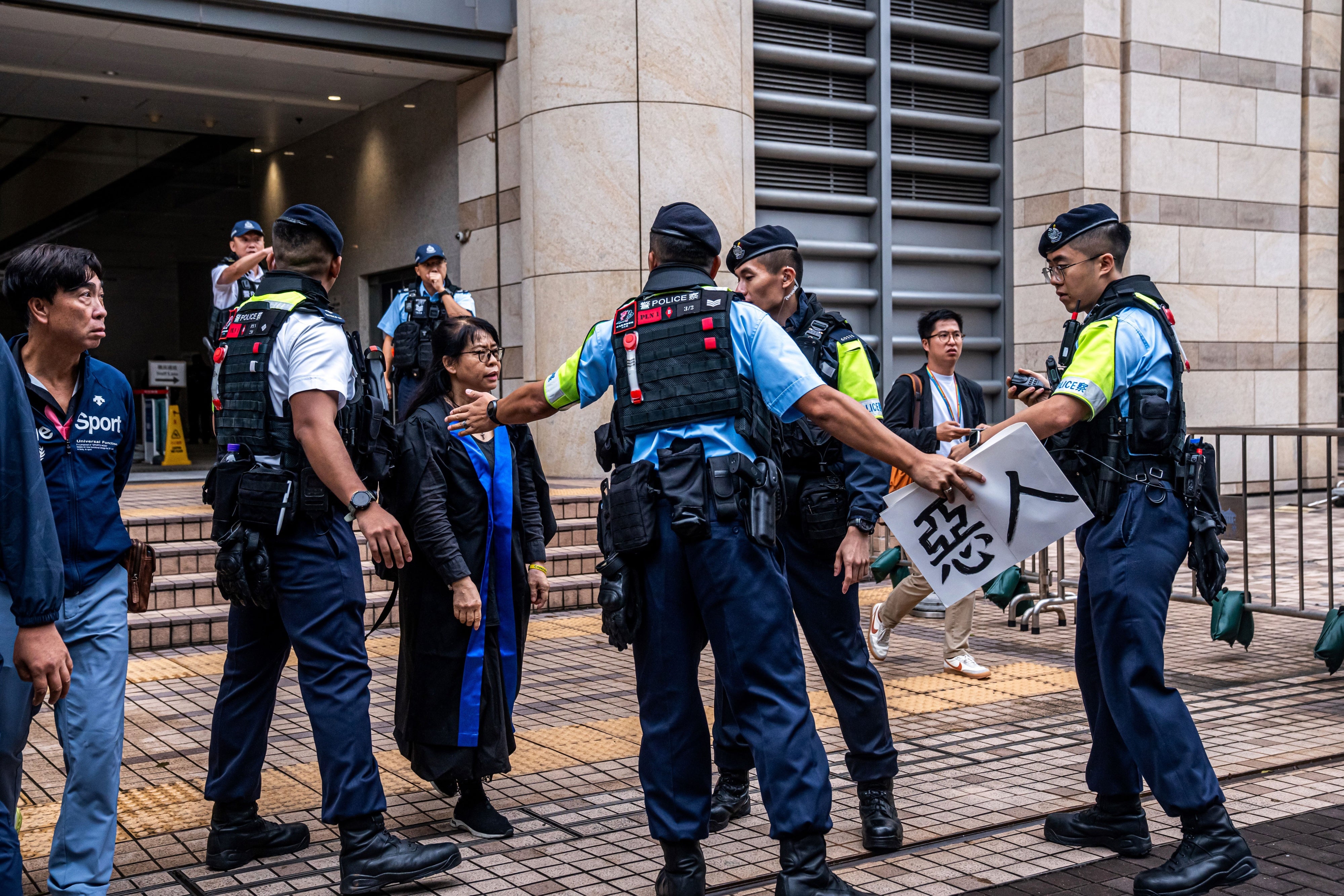 Police remove a sign from Elsa Wu, foster mother of activist Hendrick Lui
