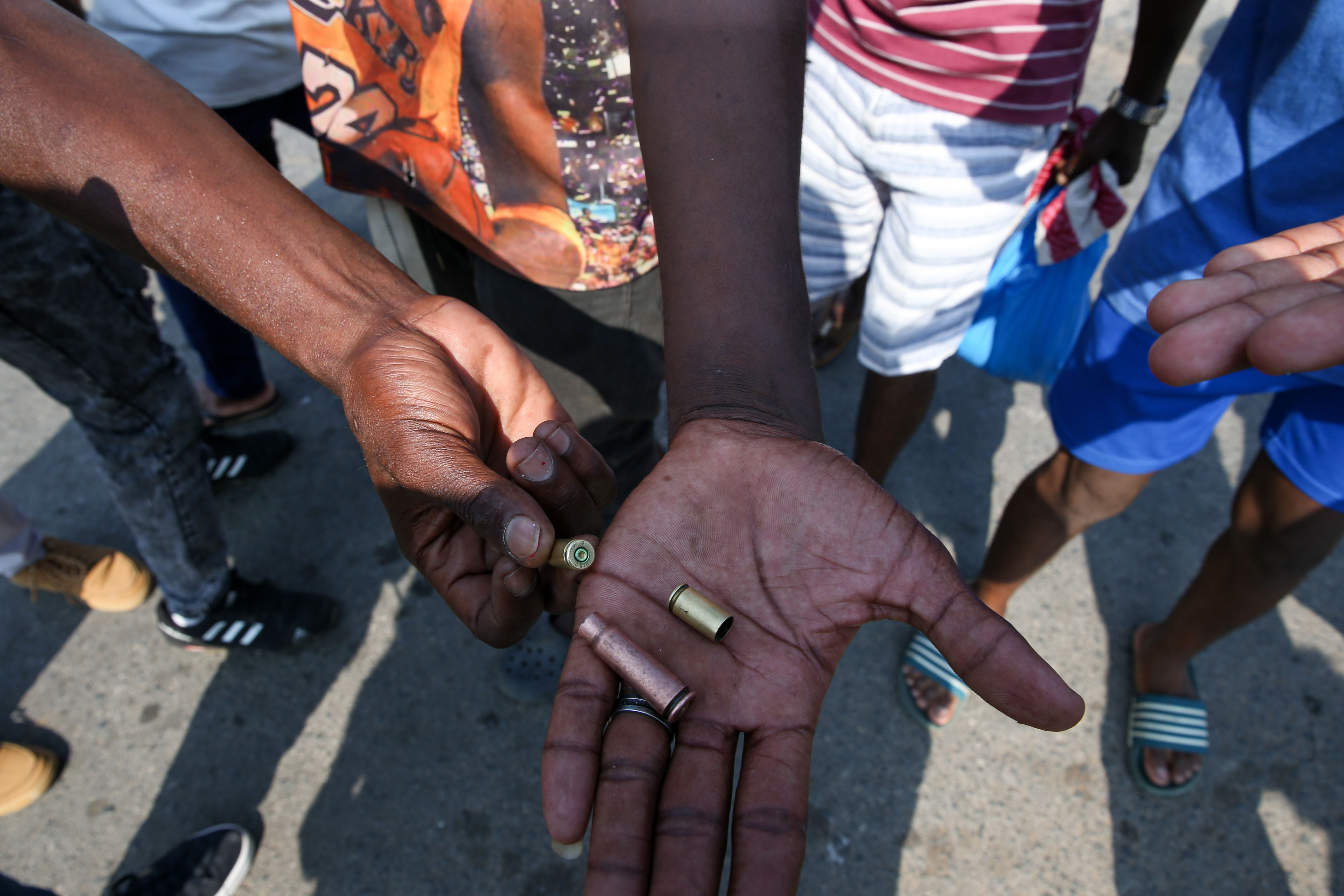 People hold pistol and rifle bullet cartridges fired by police 