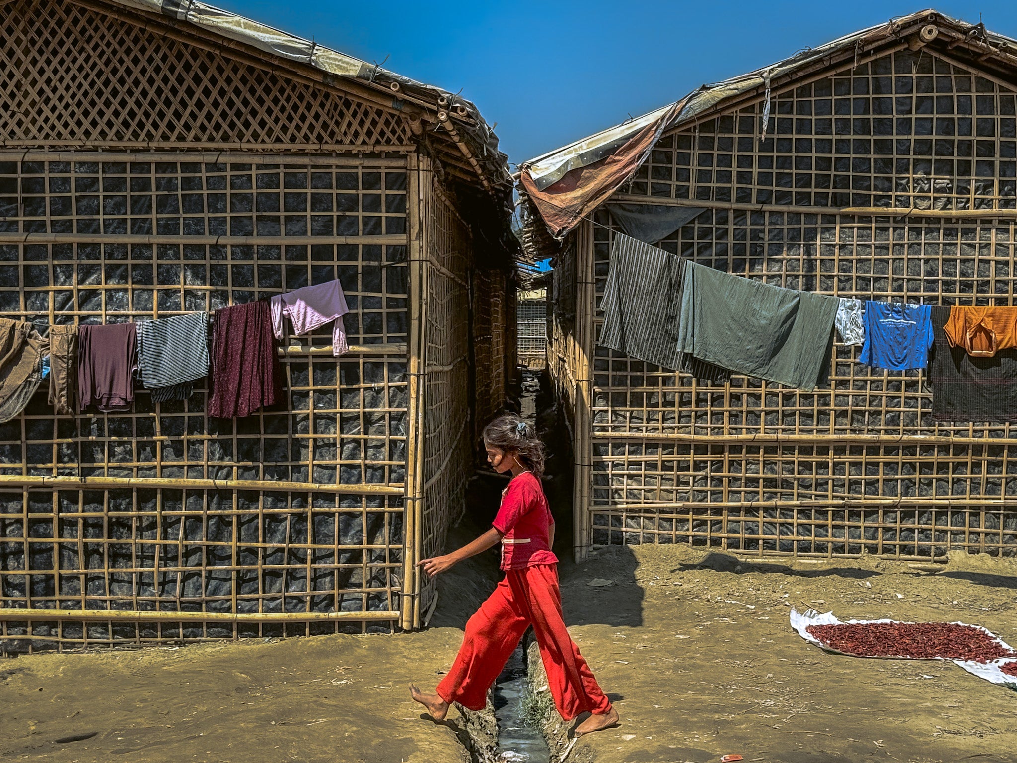A Rohingya girl walks past shelters in a refugee camp in Cox's Bazar, Bangladesh, March 9, 2025.