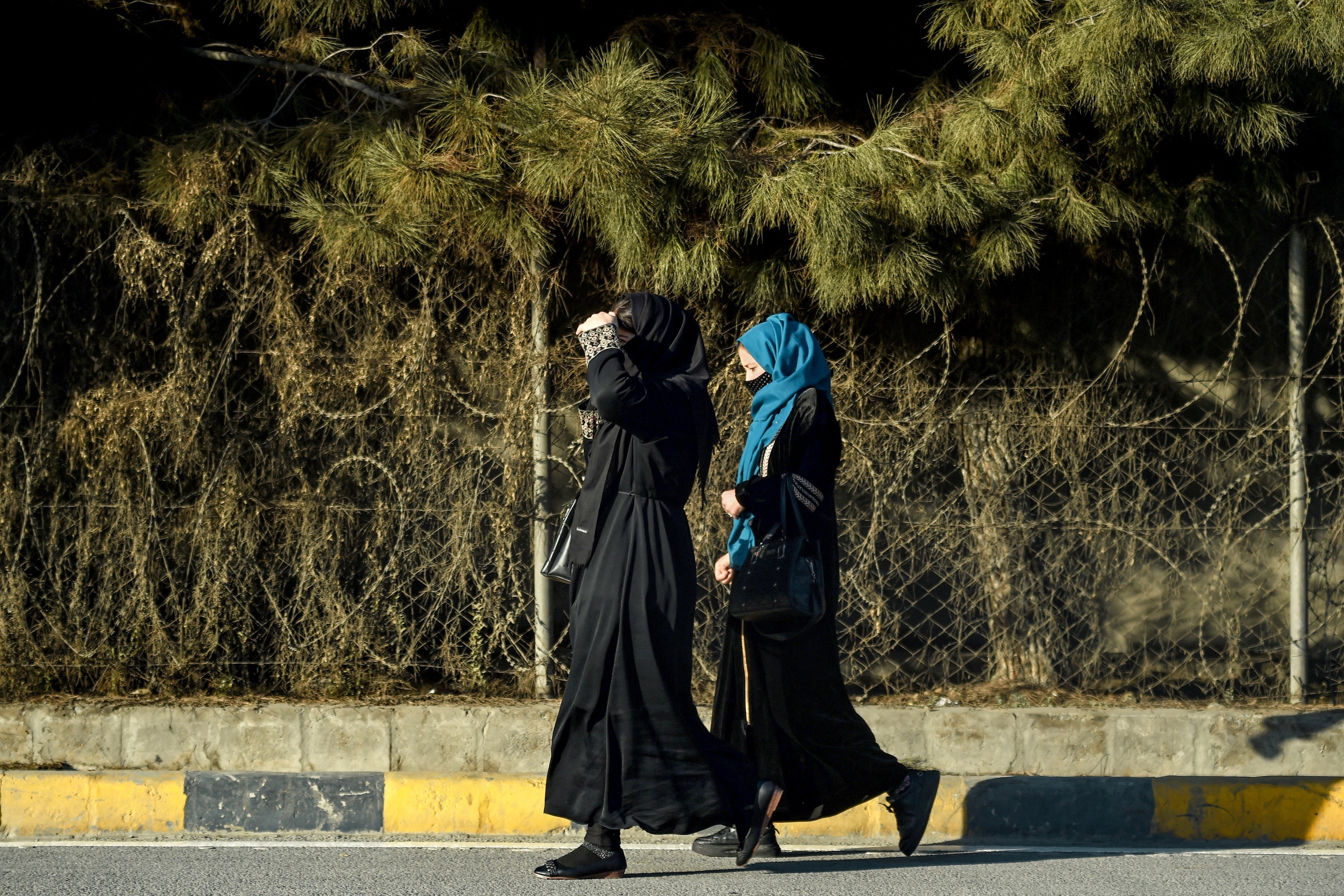 Afghan women walk past razor barricades along a roadside in Kabul on December 8, 2024.