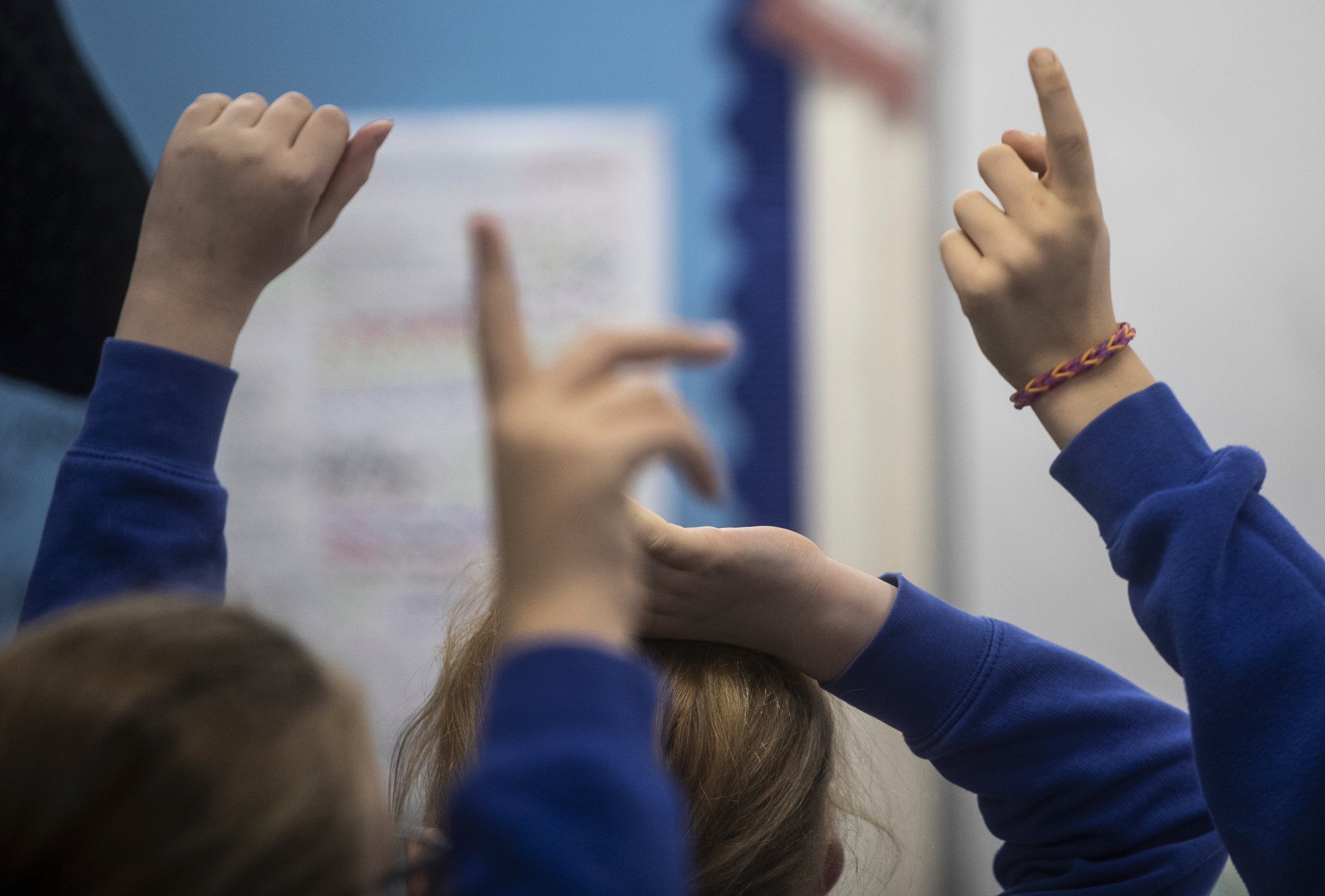 Les enfants d'une école primaire du nord de l'Angleterre lèvent la main en classe.