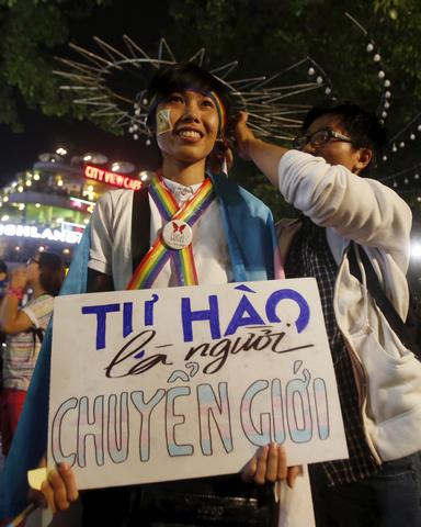 A participant holds a placard which reads "proud to be transgender" as they wait for an LGBT demonstration along a street in Hanoi.