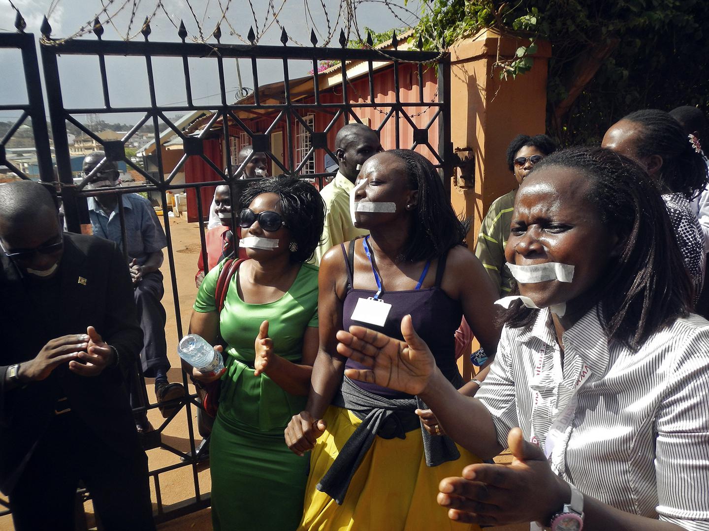 Employees of the Daily Monitor newspaper with their mouths taped shut, sing slogans during a protest against the closure of their premises by the Uganda government, outside their offices in the capital Kampala May 20, 2013. 