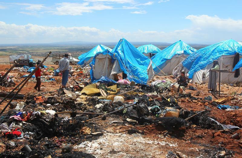 People stand near the damage after air strikes on May 5 hit a camp for internally displaced people in Syria's Idlib province near the Turkish border, May 7, 2016.