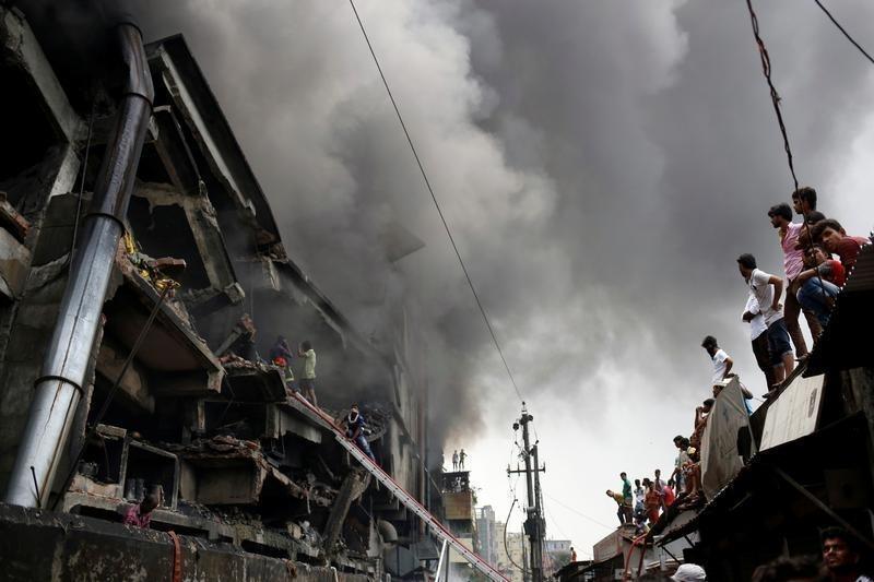 People look at a fire at a food and cigarette packaging factory outside Dhaka, Bangladesh, September 10, 2016.