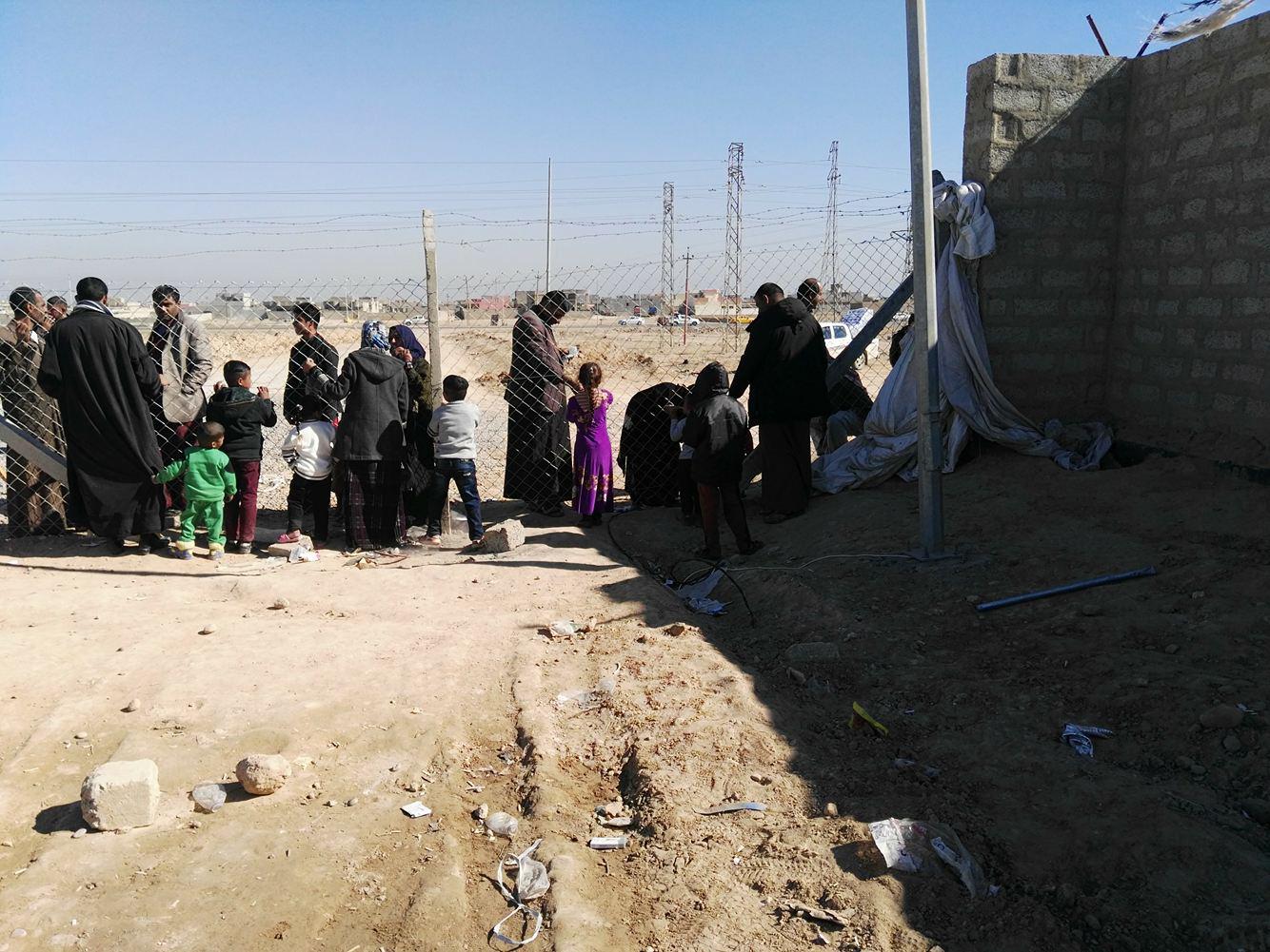 Residents of Shahama camp speak with relatives through the camp fence. 