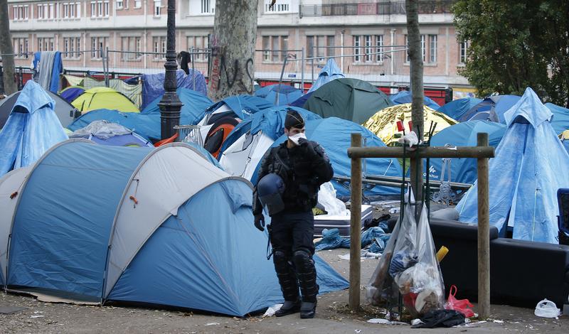 French riot police officer stands guard next to tents of a dismantled makeshift camp in a street near Stalingrad metro station, Paris, France, November 4, 2016. 