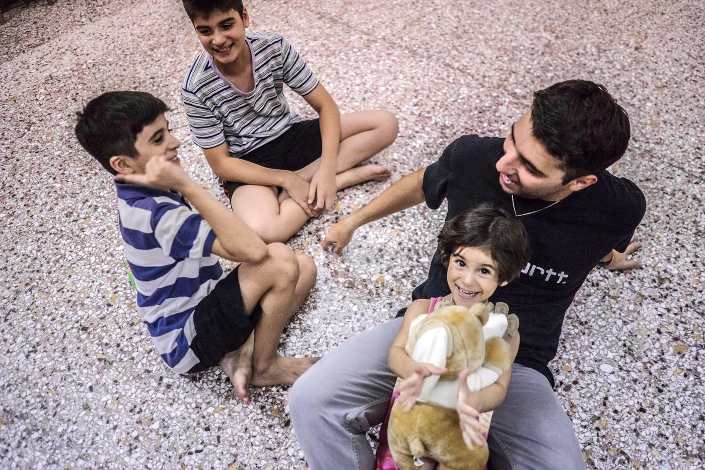 Alexandros plays with Evin, Rudi and Mohammed in Falak’s temporary accommodation in Aigaleo, Greece. © 2017 Anna Pantelia