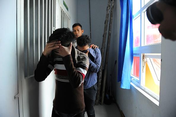 Two Indonesian men walk into a cell prior to their trials at a shariah court in Banda Aceh on May 17, 2017. 