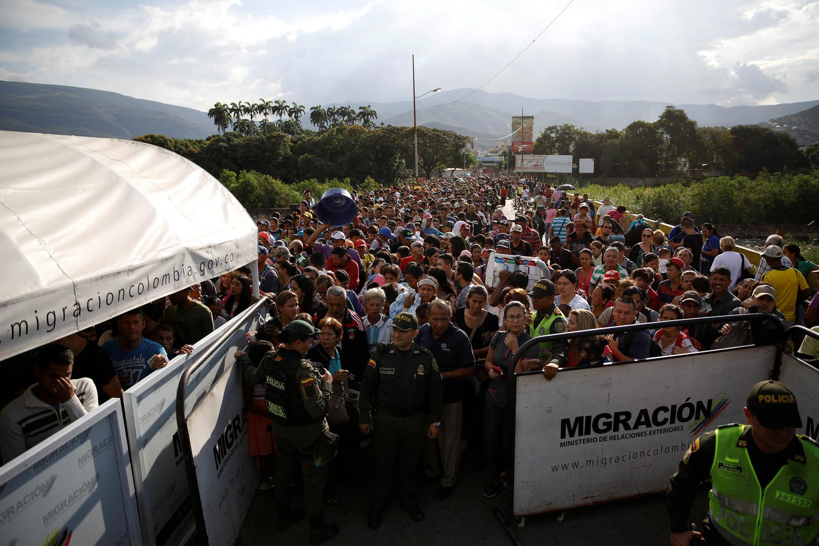 Colombian police officers stand in front of people queueing to try to cross into Colombia from Venezuela through the Simon Bolivar international bridge in Cucuta, Colombia. January 24, 2018.