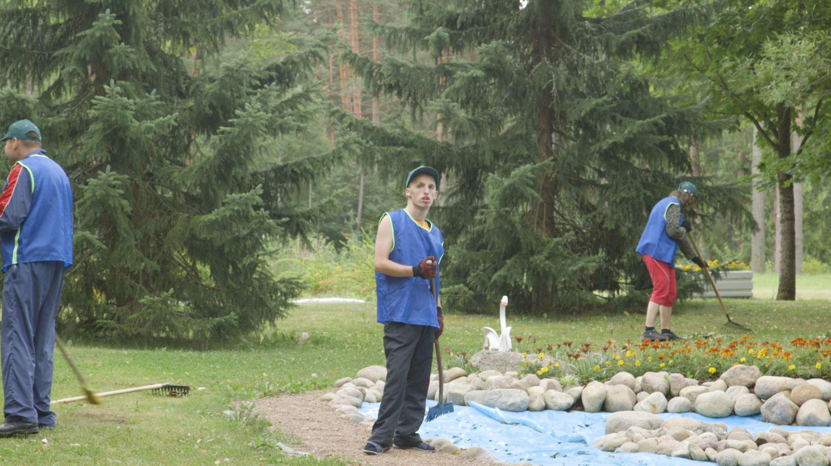 A young man does yard work on the grounds of a closed state institution for adults with disabilities.