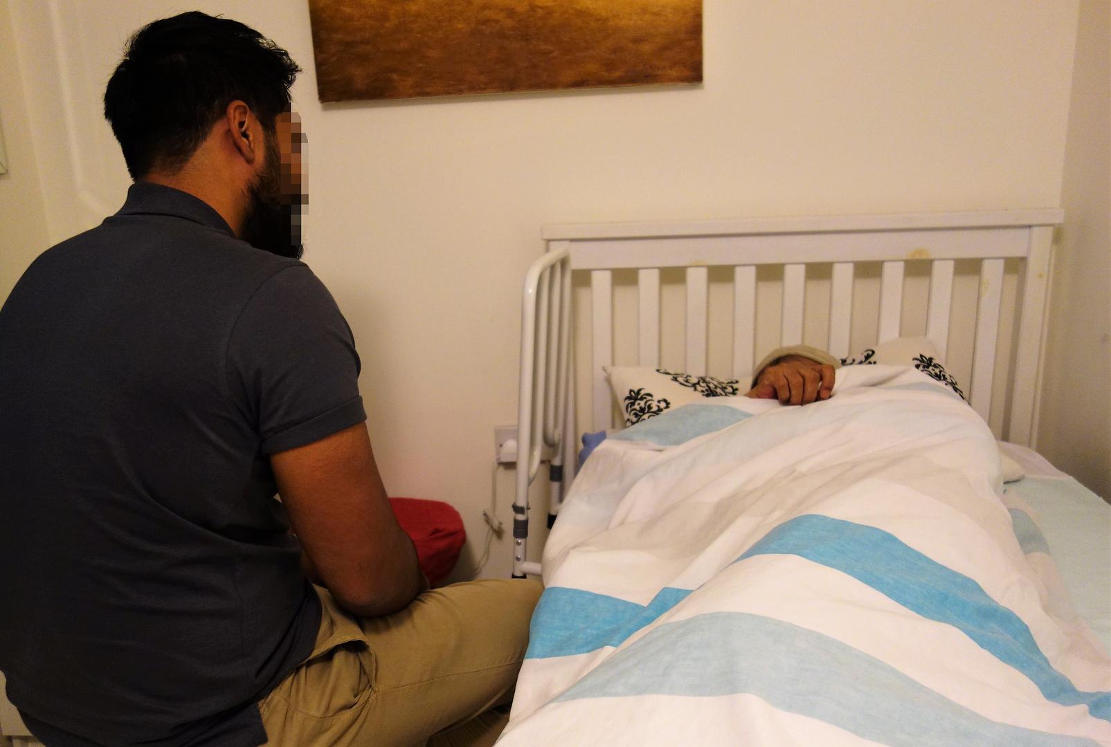 Mohammed sits with his father, Farhaz, at their home in east London. Farhaz suffers from severe dementia.  © 2018 Stephanie Hancock/Human Rights Watch