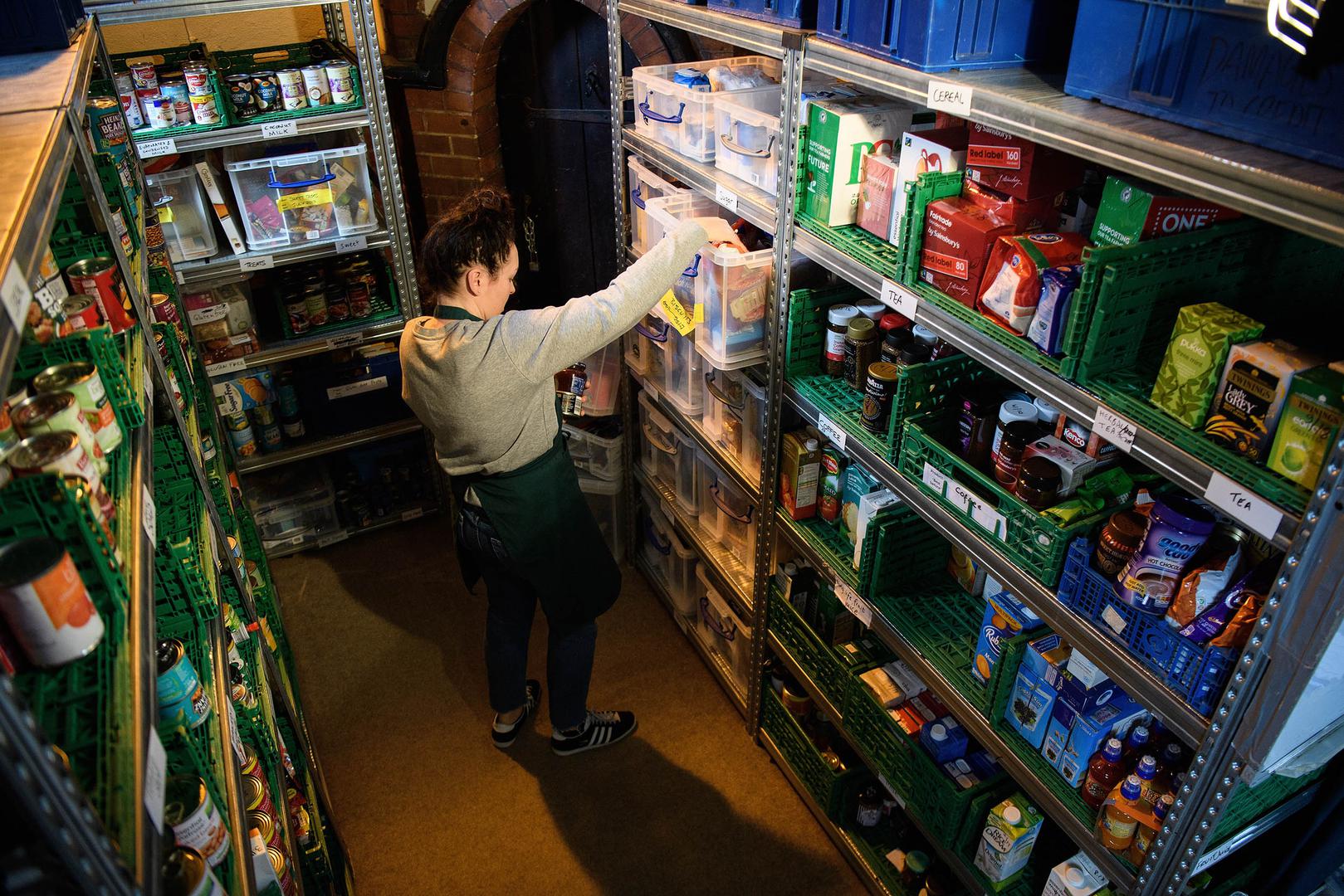 A volunteer at a Trussell Trust food bank prepares food parcels from their stores of donated food, toiletries and other items. London, United Kingdom. 
