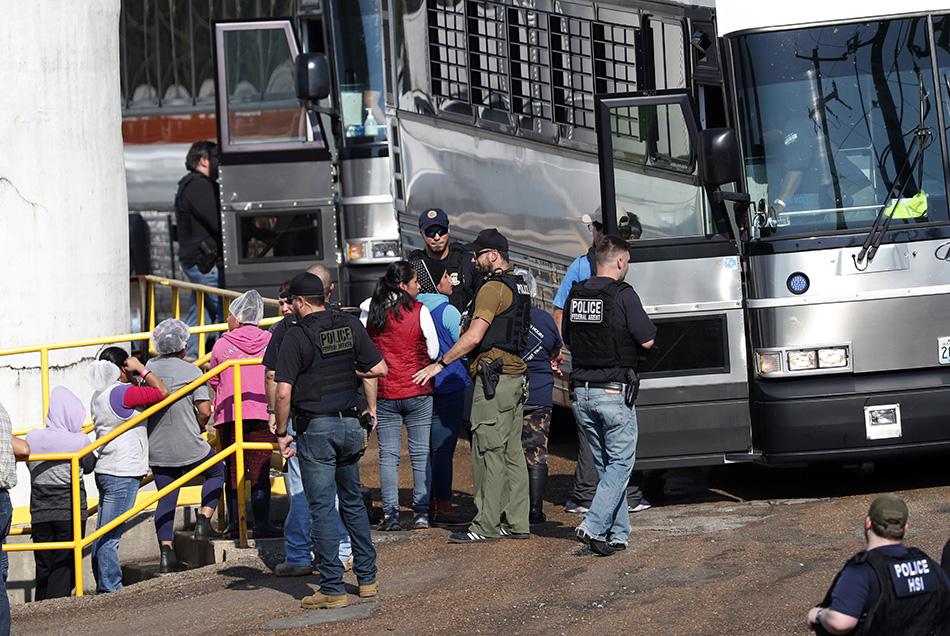 Workers are escorted onto a bus for transportation to a processing center following a raid by US immigration officials