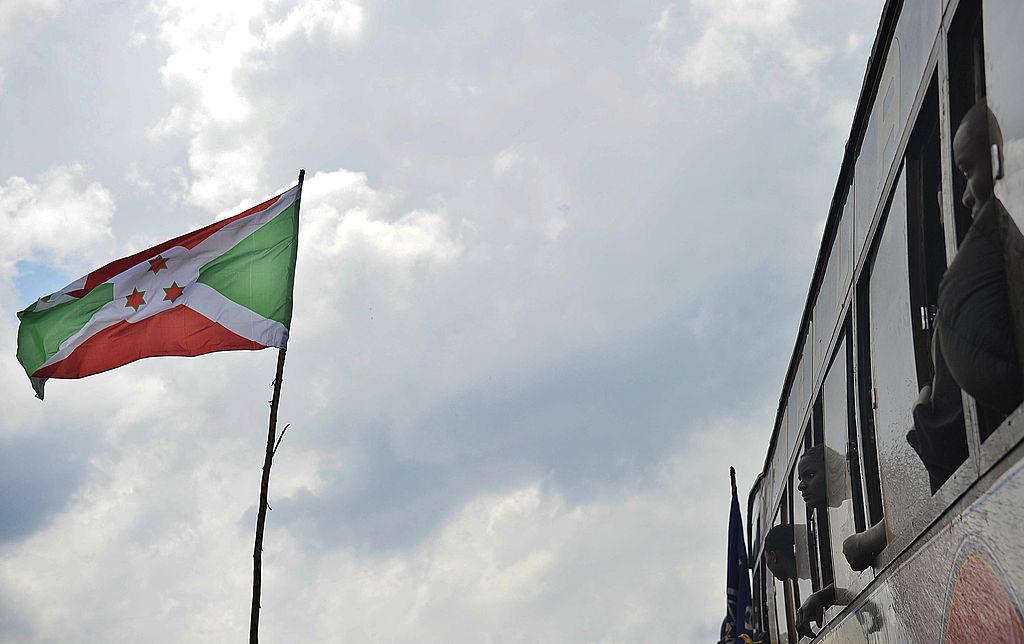 Burundian refugees who returned from a camp in Tanzania look at the flag of Burundi after arriving by bus at a transit camp in Musenyi, southern Burundi, November 14, 2012.