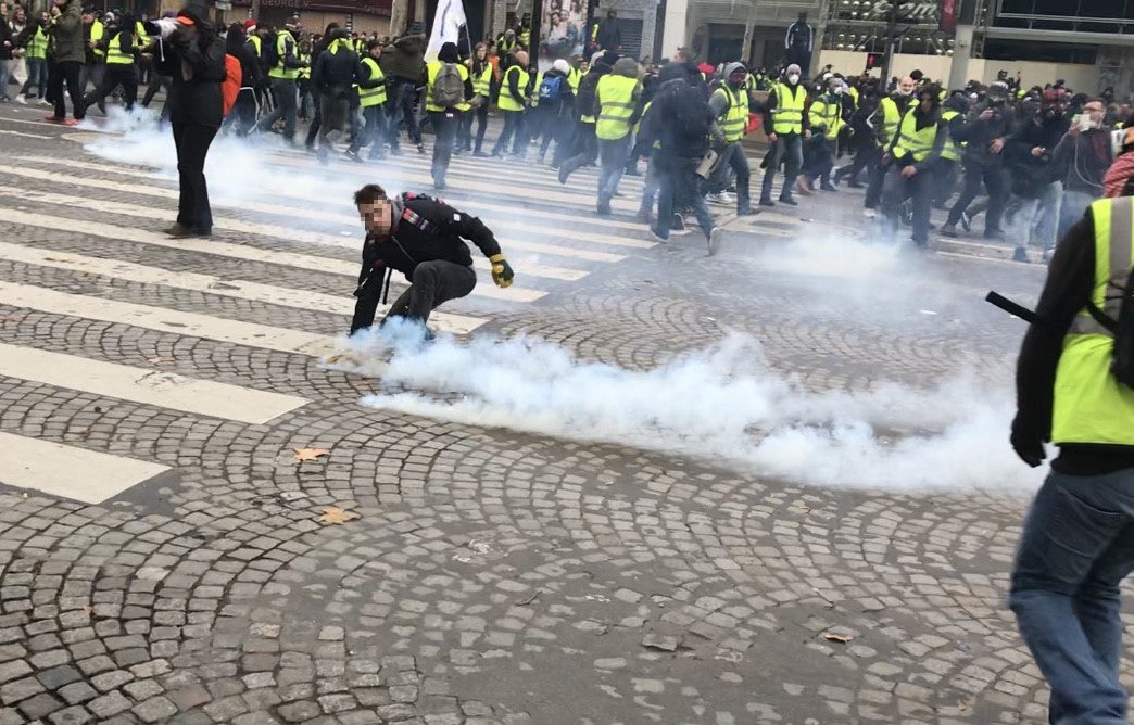 Un manifestant ramasse une grenade lacrymogène lors d'une charge de police, le 8 décembre 2019 sur les Champs Elysées, à Paris.