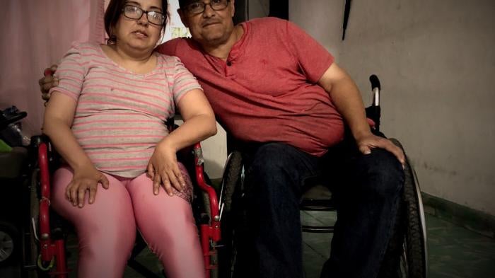 A man and woman pose in wheelchairs