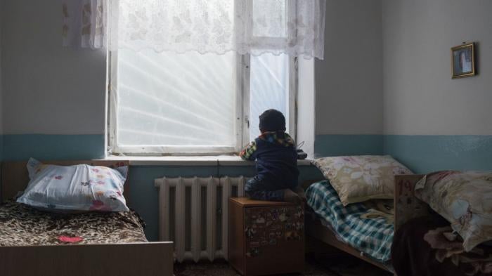 A child stares out a bedroom window