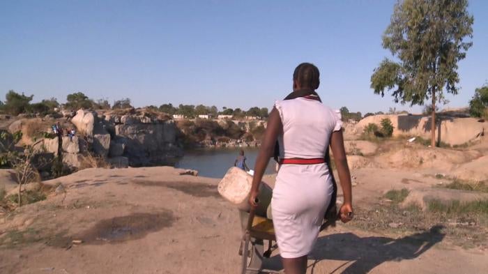 A woman with a wheelbarrow goes to collect water in Harare, Zimbabwe.