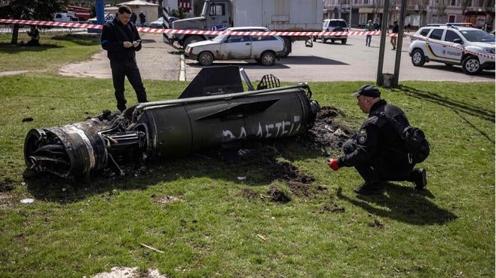 Ukrainian authorities inspect the rocket motor and guidance section of a Tochka-U missile next to the main building of the Kramatorsk train station in eastern Ukraine on April 8, 2022. The phrase “Payback for the children” is painted in Russian on the missile. 